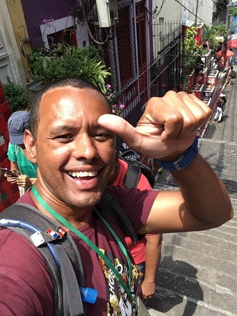 A man with a backpack is smiling and giving a thumbs up