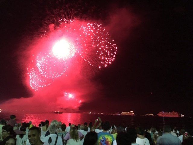 A crowd of people watching fireworks over a body of water