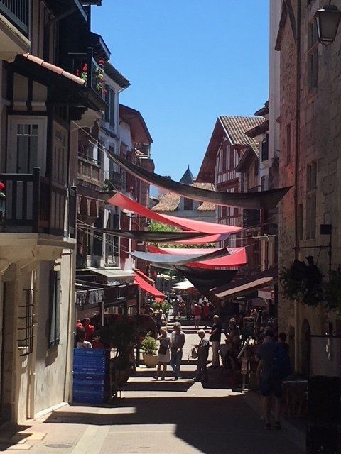A narrow street with a lot of people walking down it