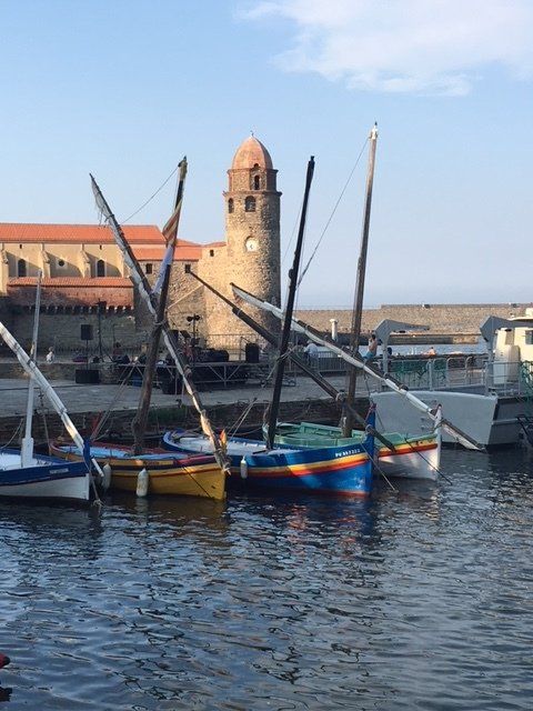 Several boats are docked in a harbor with a clock tower in the background