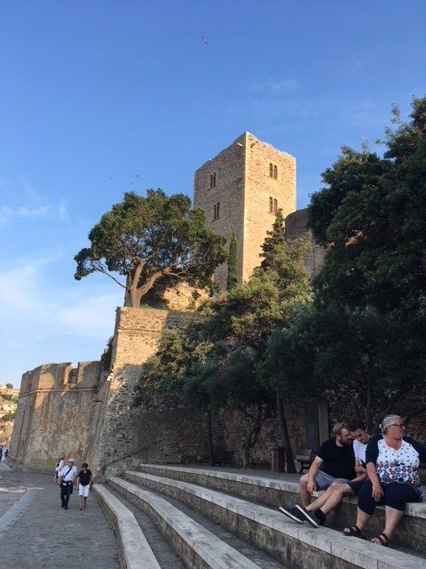 A group of people are sitting on steps in front of a castle.