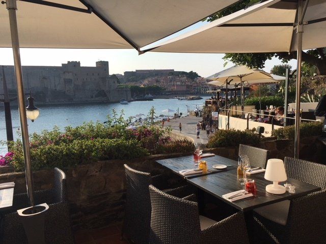 A restaurant with tables and chairs and umbrellas overlooking a body of water