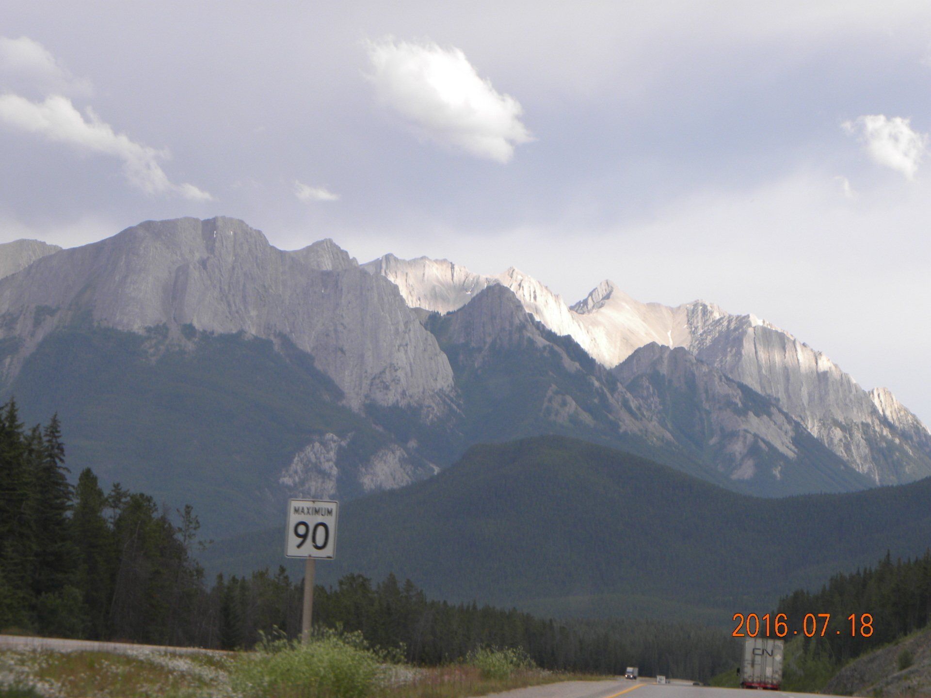 A road with mountains in the background and a sign that says 90