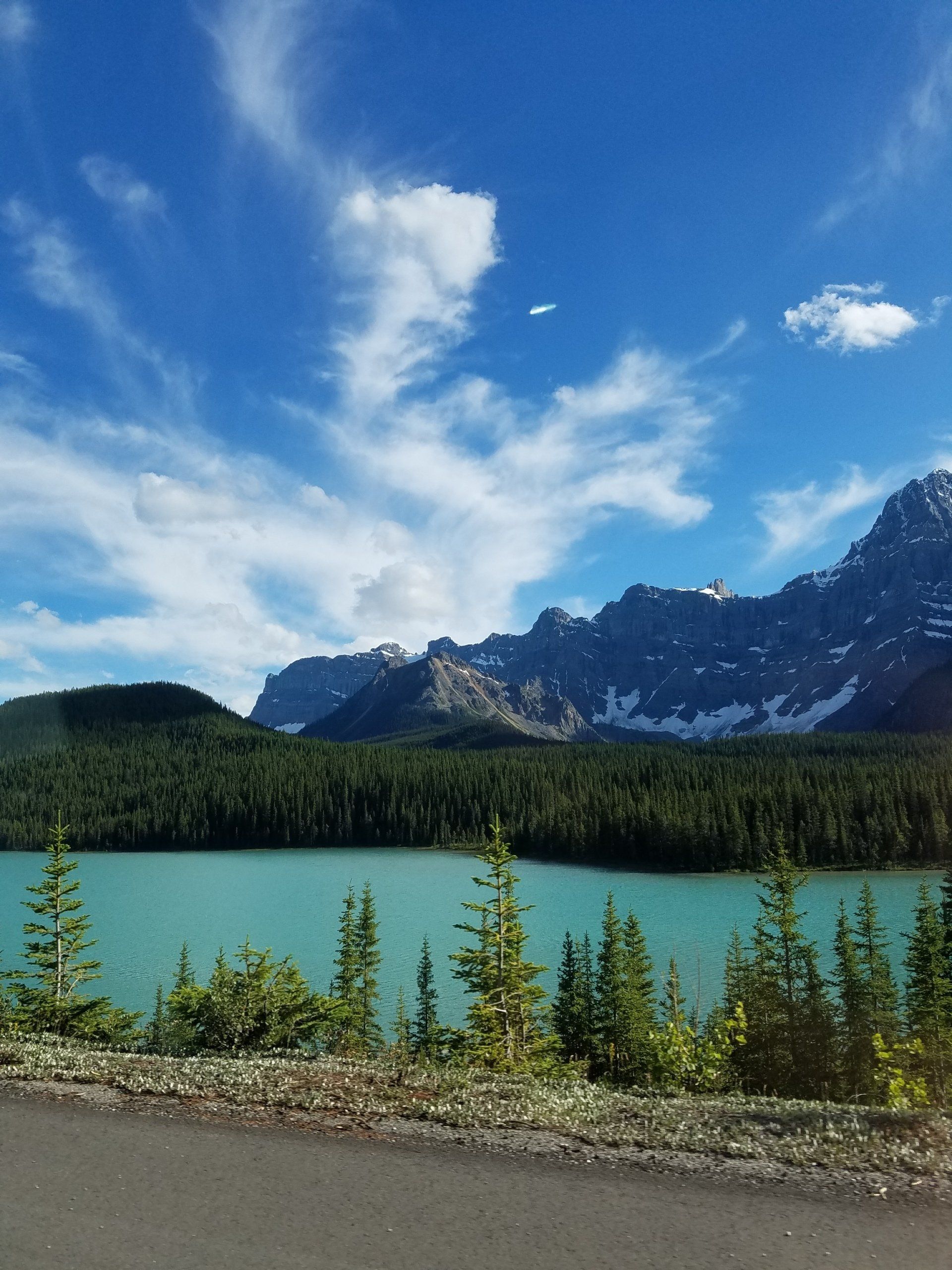 A lake surrounded by mountains and trees on a sunny day