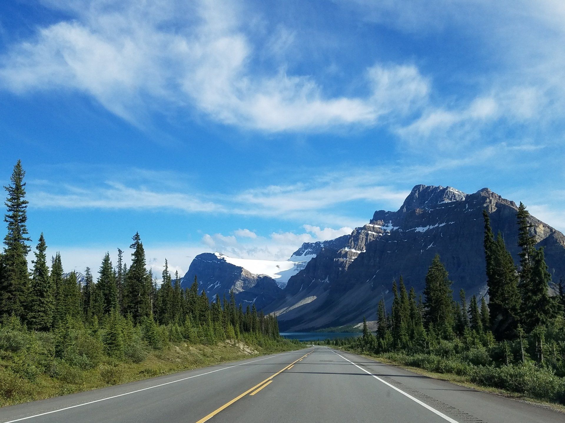 A road with mountains in the background and trees on the side