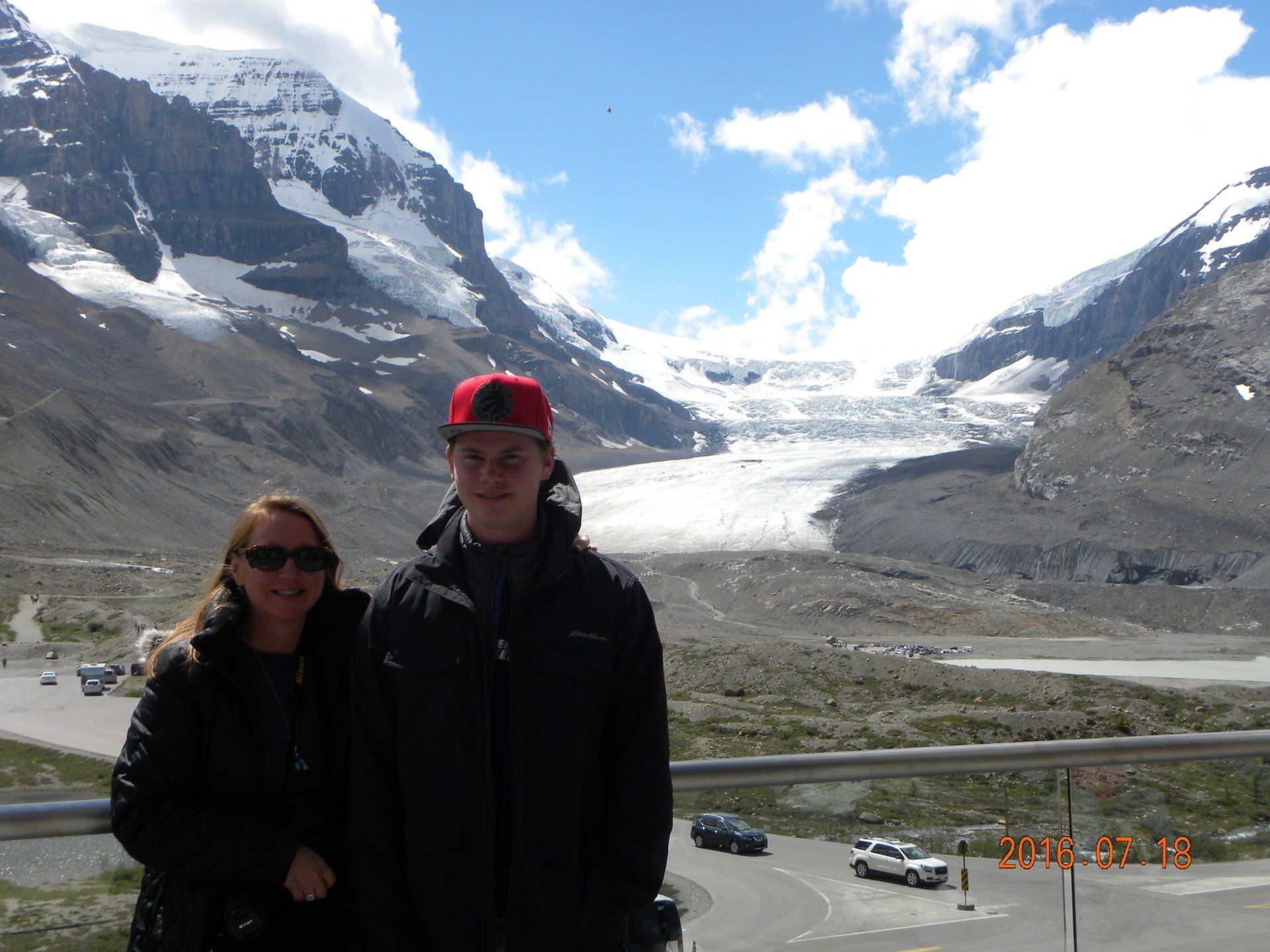 A man and a woman are posing for a picture in front of a mountain.