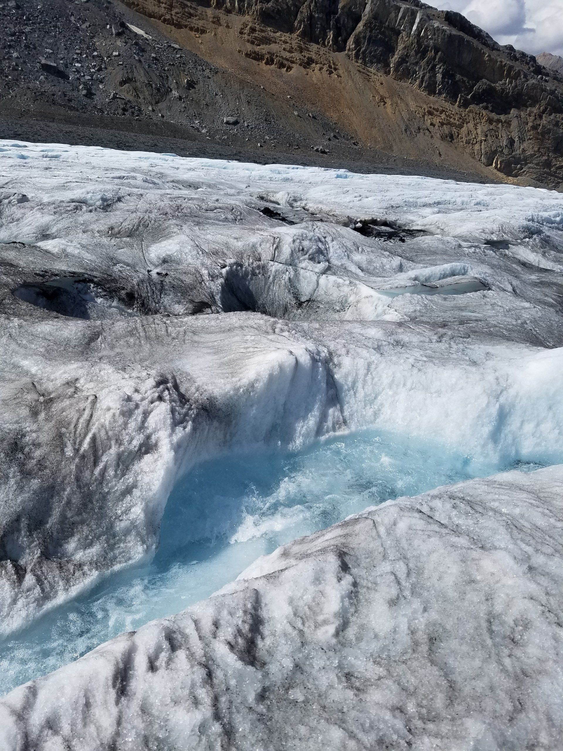 A river flowing through a glacier with a mountain in the background.