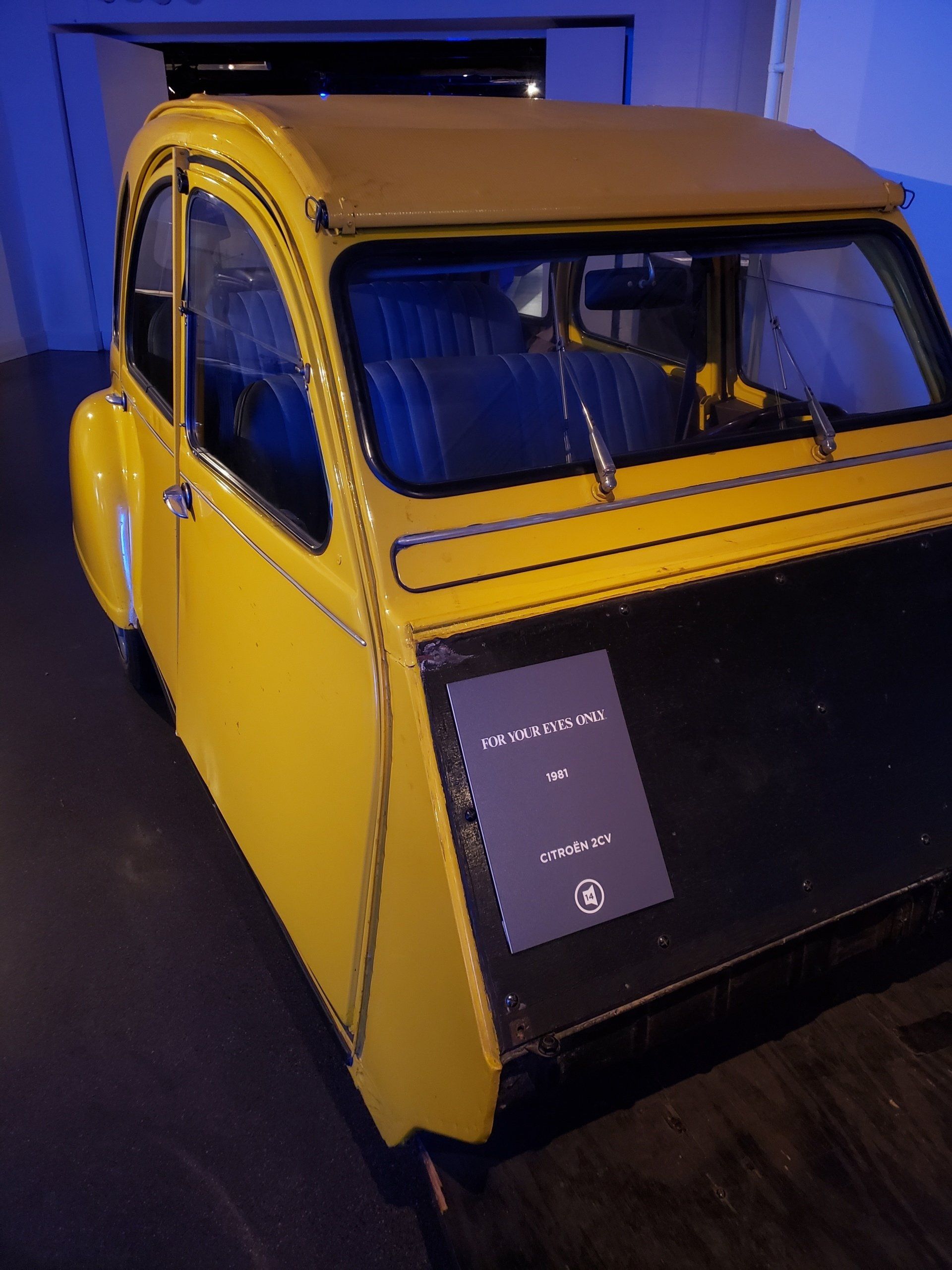 A yellow car is parked in a dark room