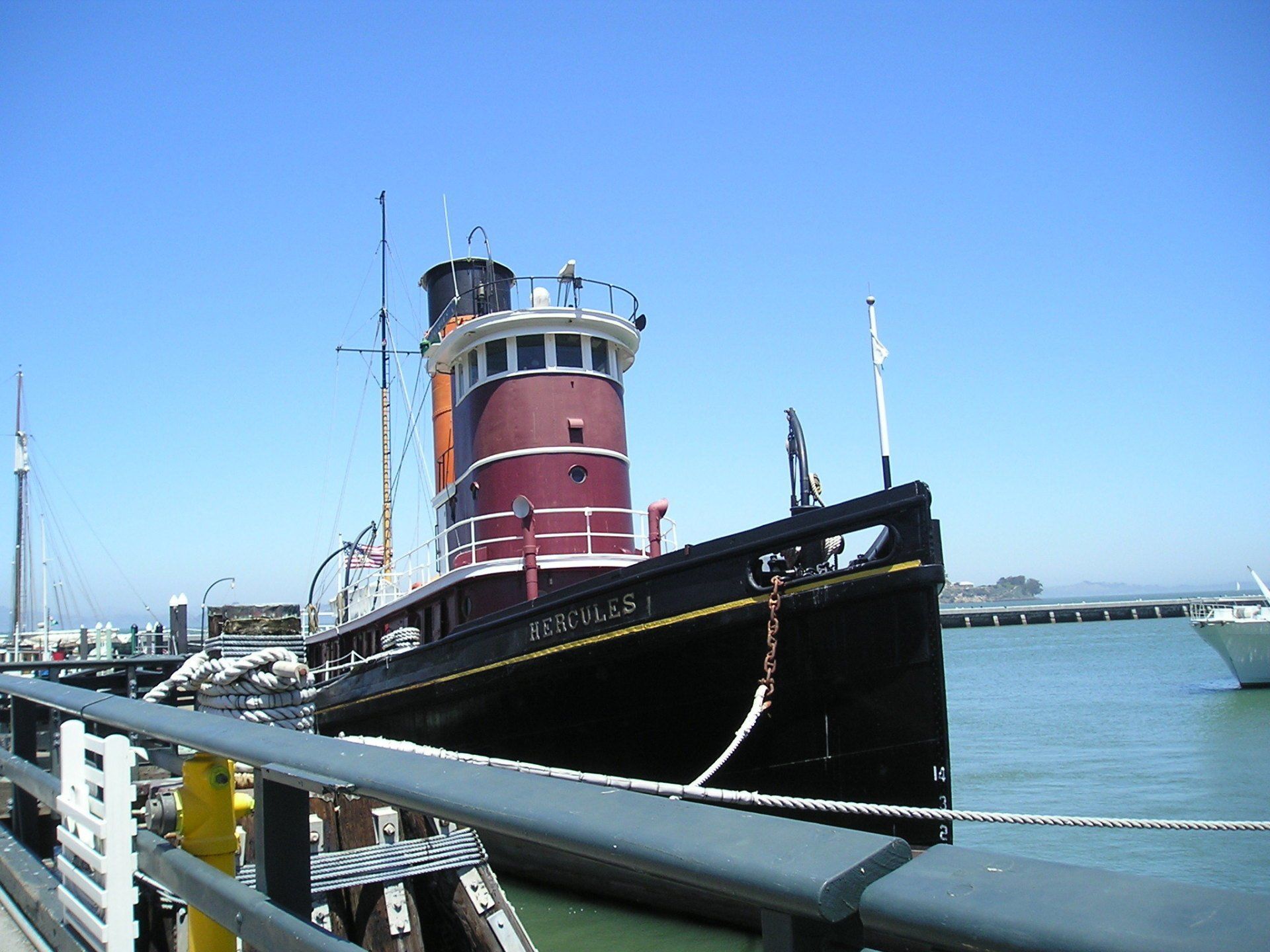 A large red and black tugboat is docked in the water
