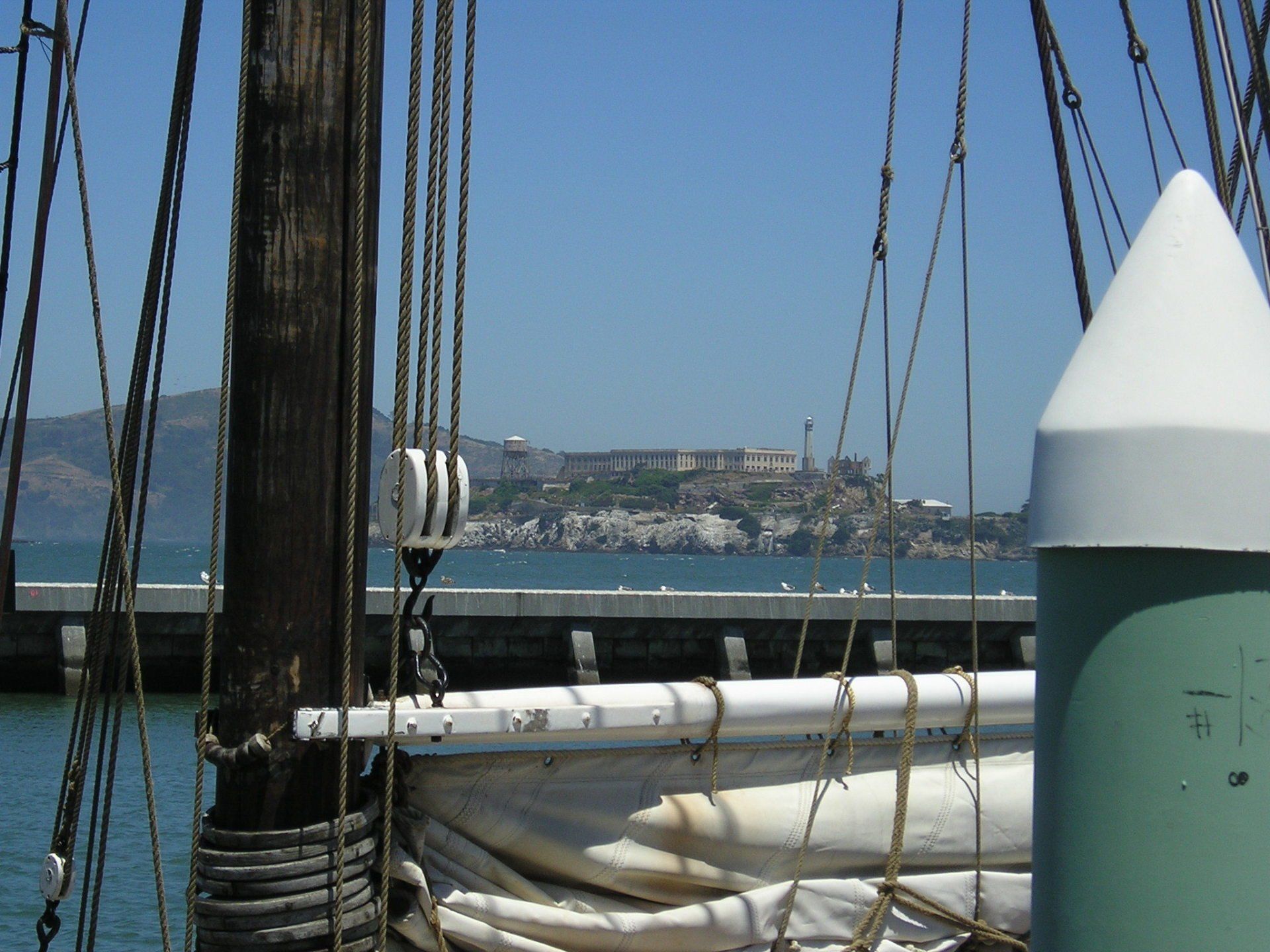 A boat is docked at a dock with a green buoy in the foreground