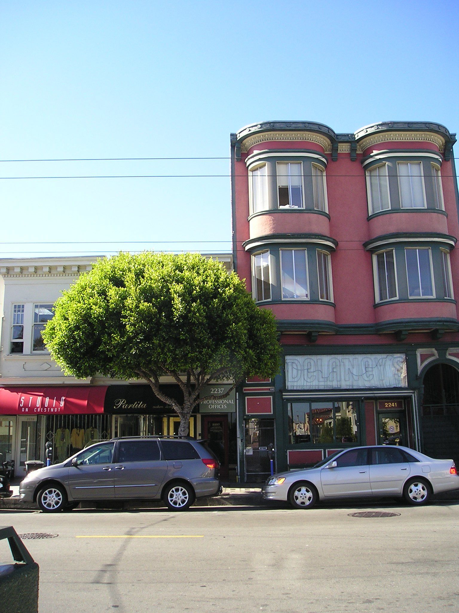 A row of cars are parked in front of a building with a sign that says ' a ' on it