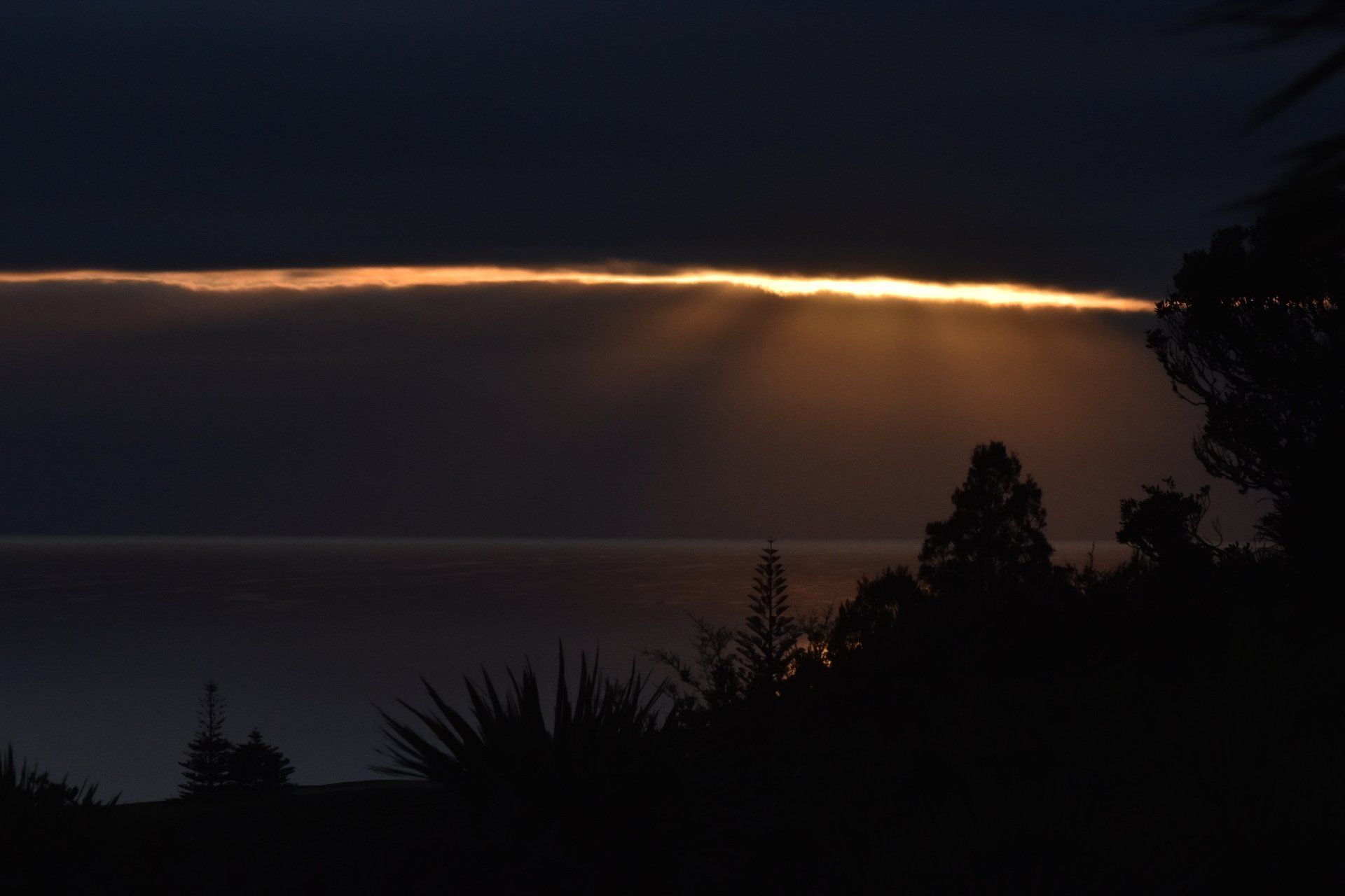 The sun is shining through the clouds over the ocean