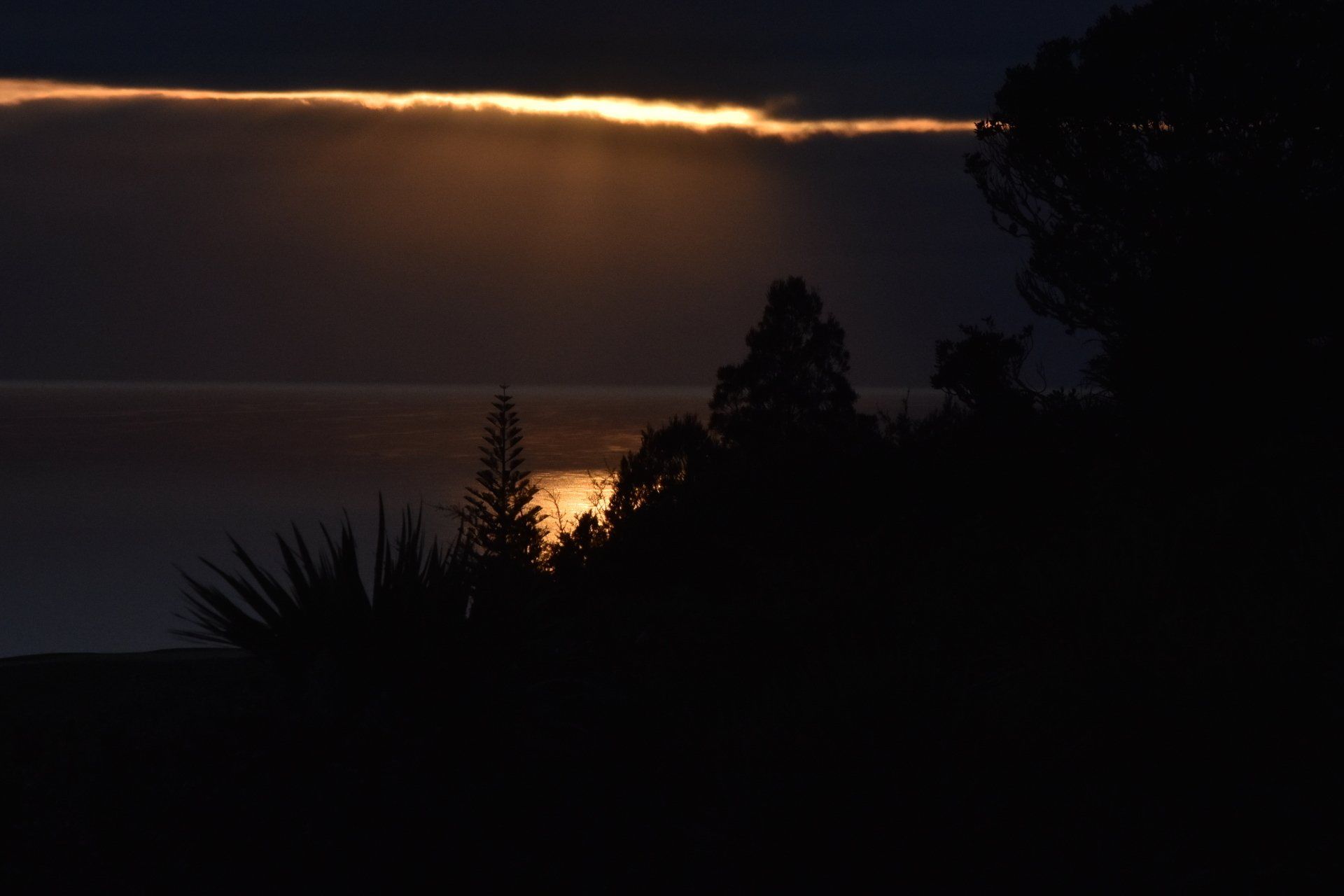 The sun is shining through the clouds in the night sky