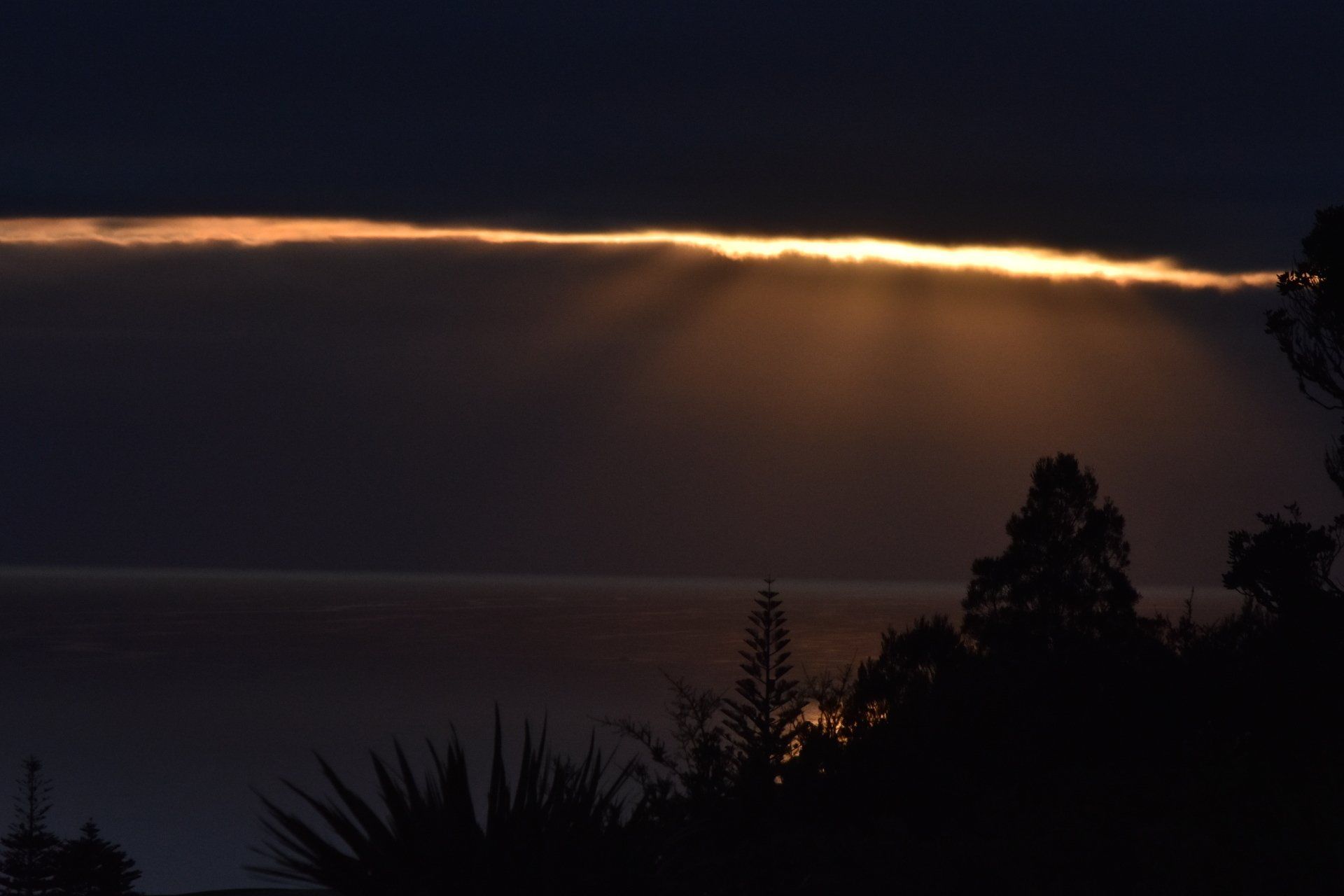 The sun is shining through the clouds over the ocean