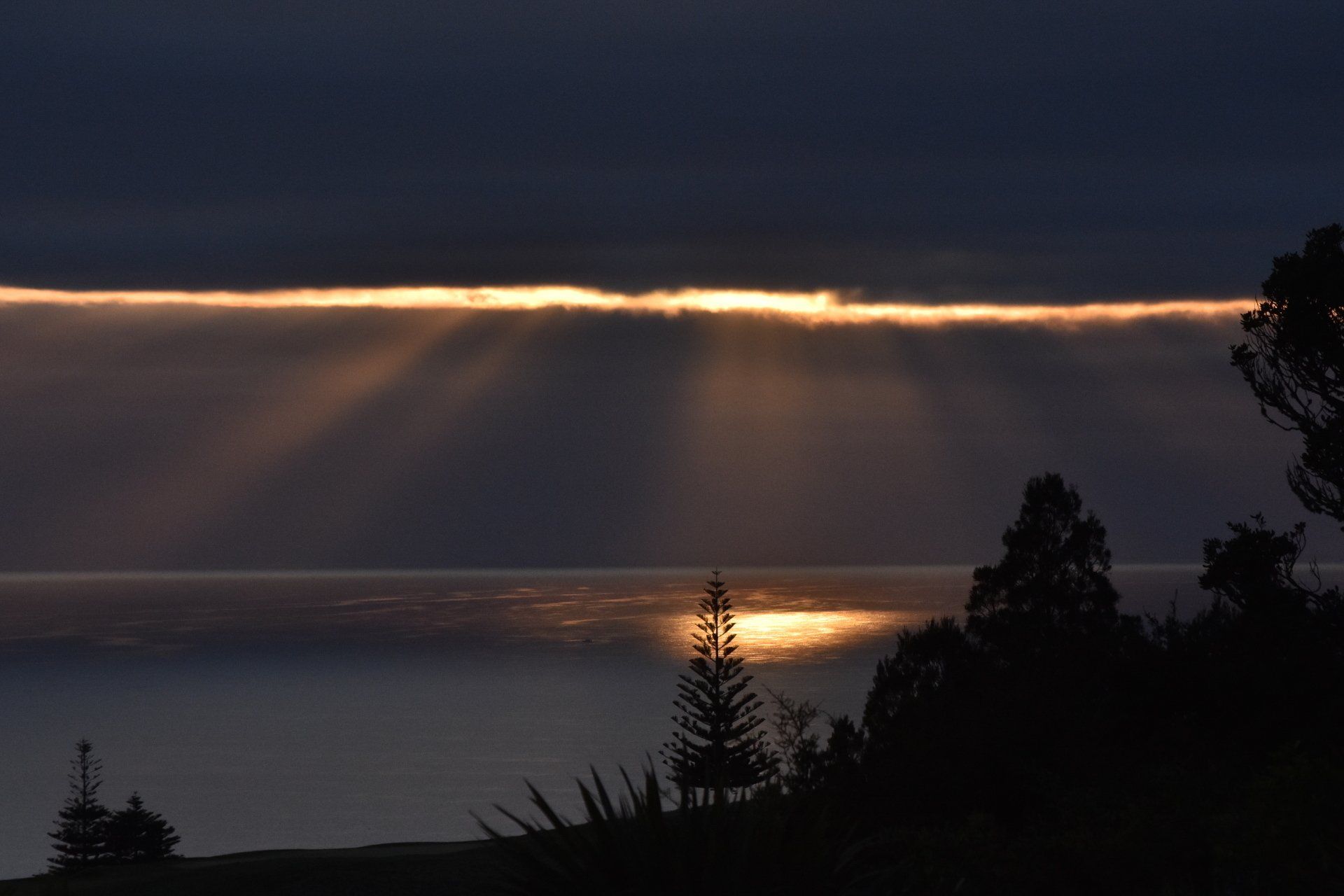 The sun is shining through the clouds over the ocean