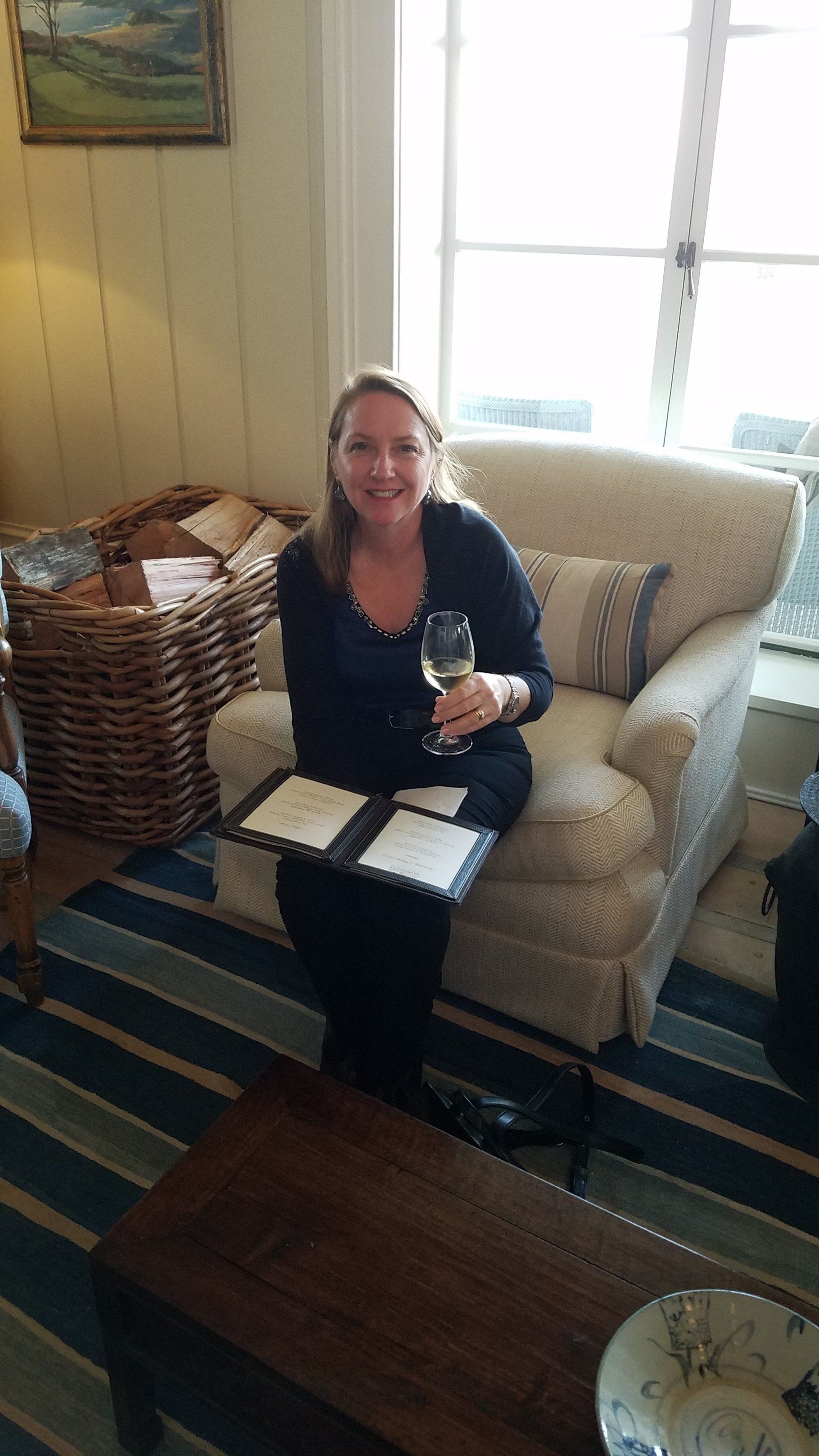 A woman is sitting on a couch holding a glass of wine.