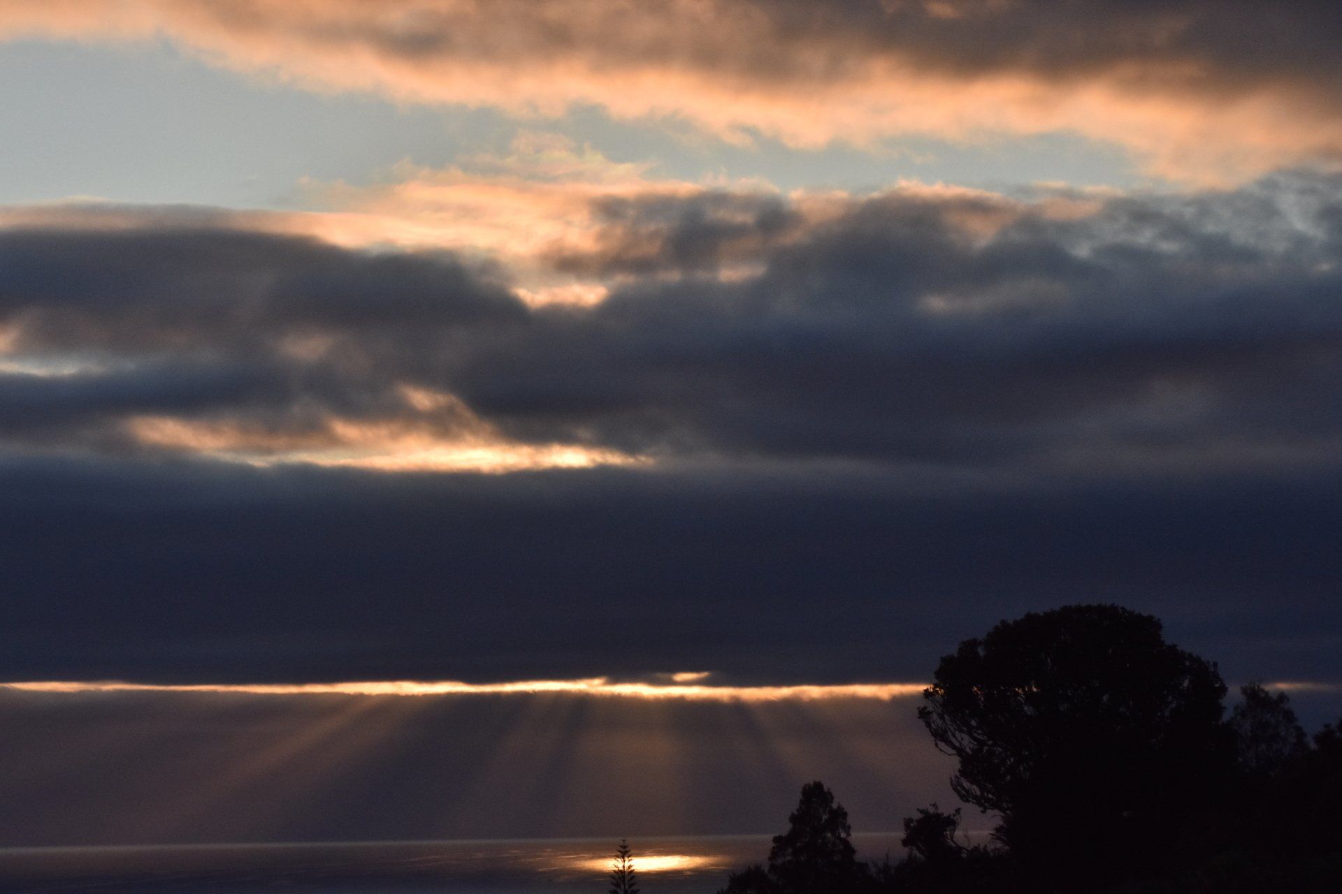 The sun is shining through the clouds at sunset