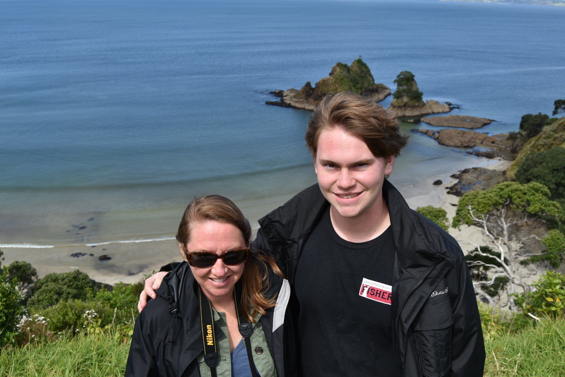 A man and a woman are posing for a picture in front of a body of water.