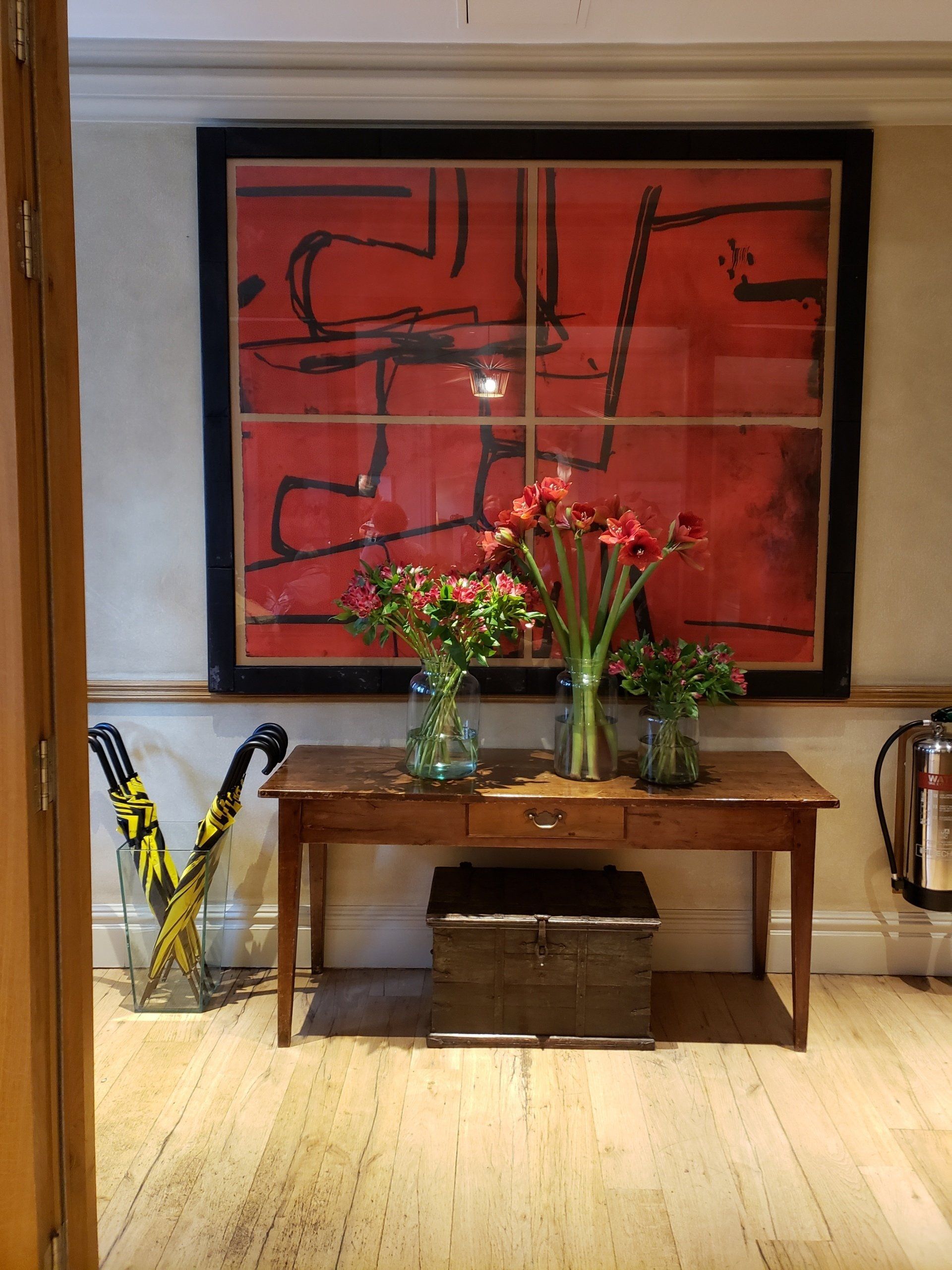A table with flowers on it in front of a large red painting