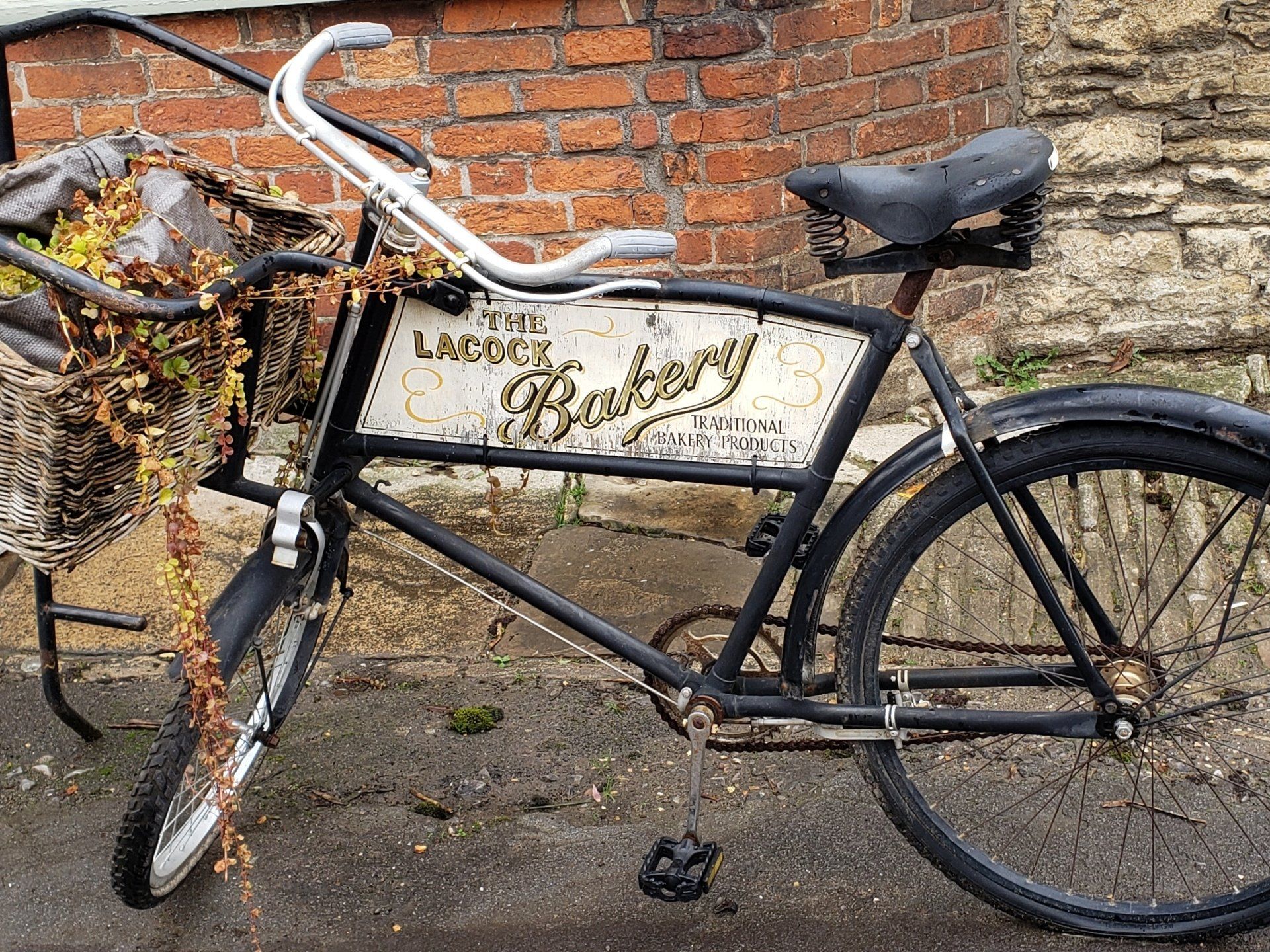 A black bicycle is parked in front of a brick wall.