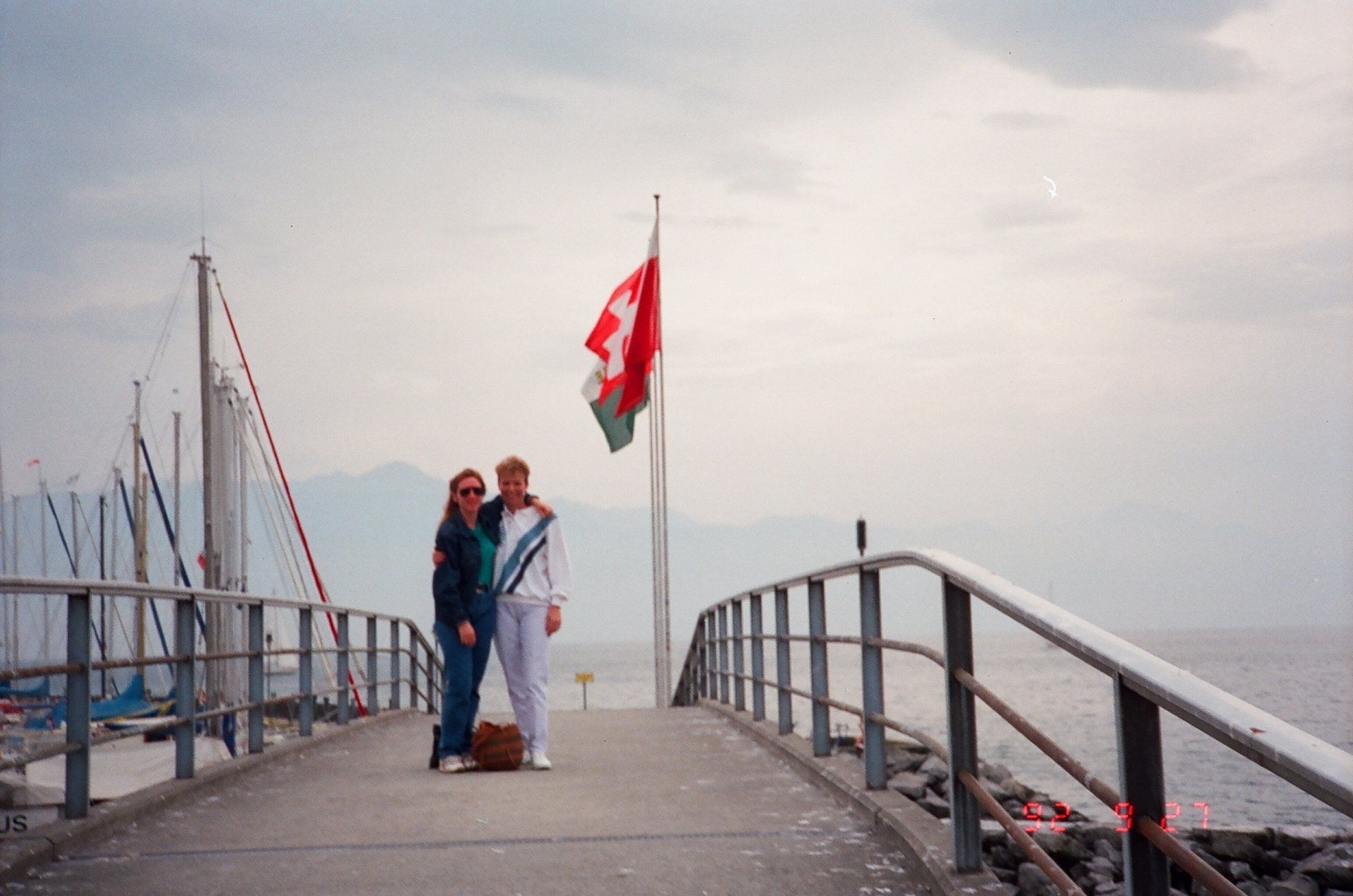Two people standing on a pier with a canadian flag in the background