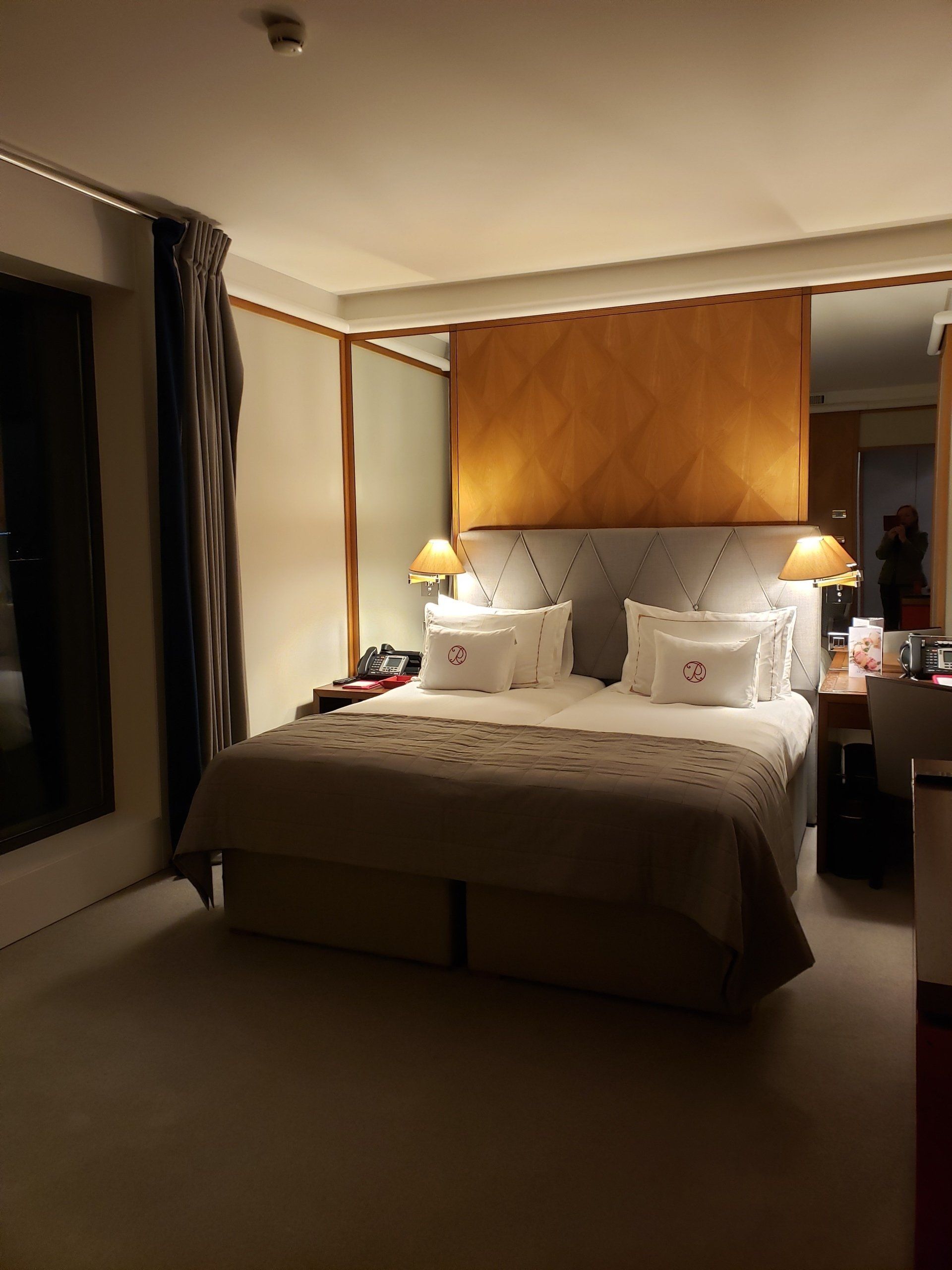 A hotel room with a large bed and two lamps