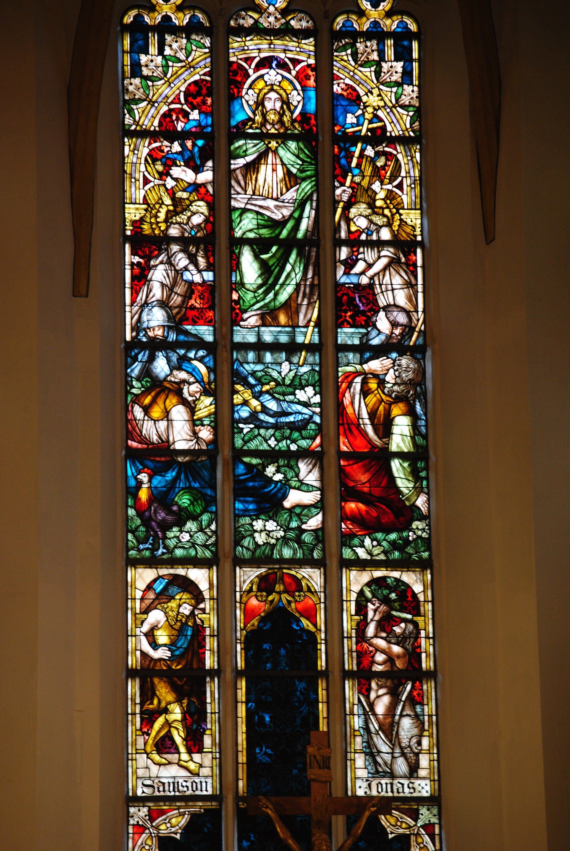 A stained glass window in a church with jesus on the cross