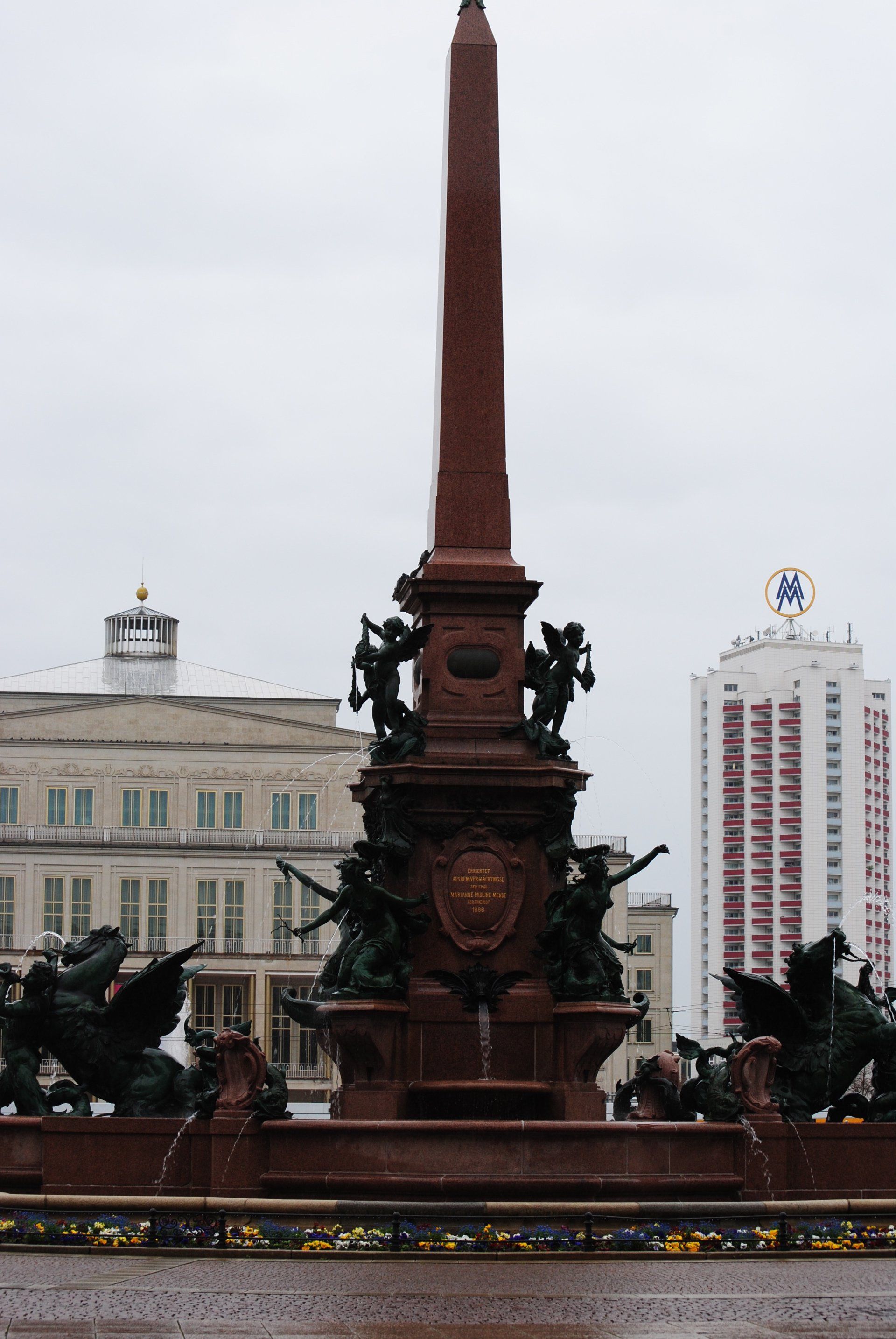 A large obelisk with a shield on it in front of a building