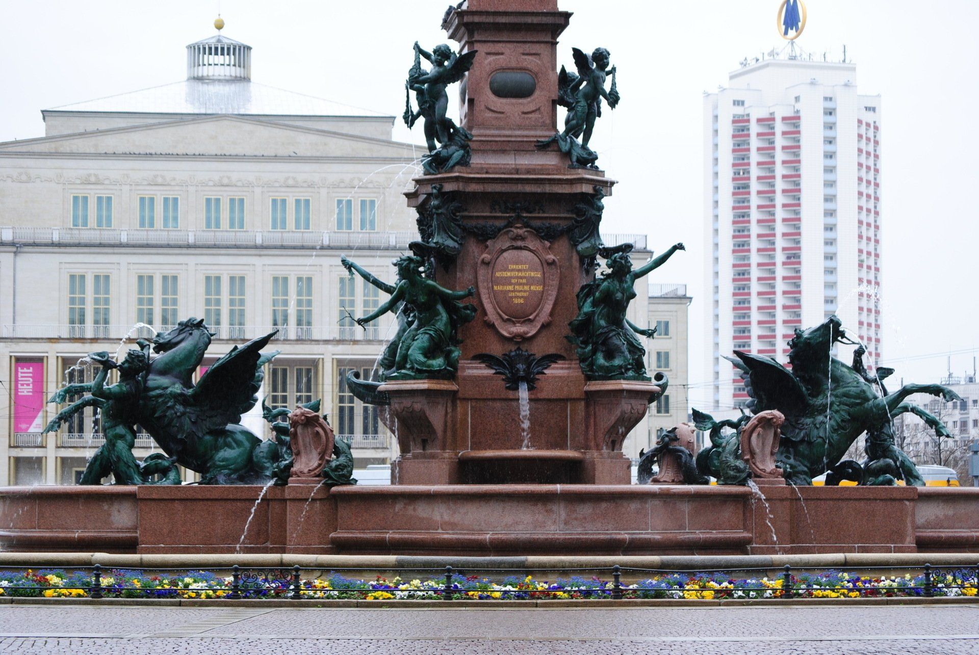 A fountain in front of a building with a statue of people on it