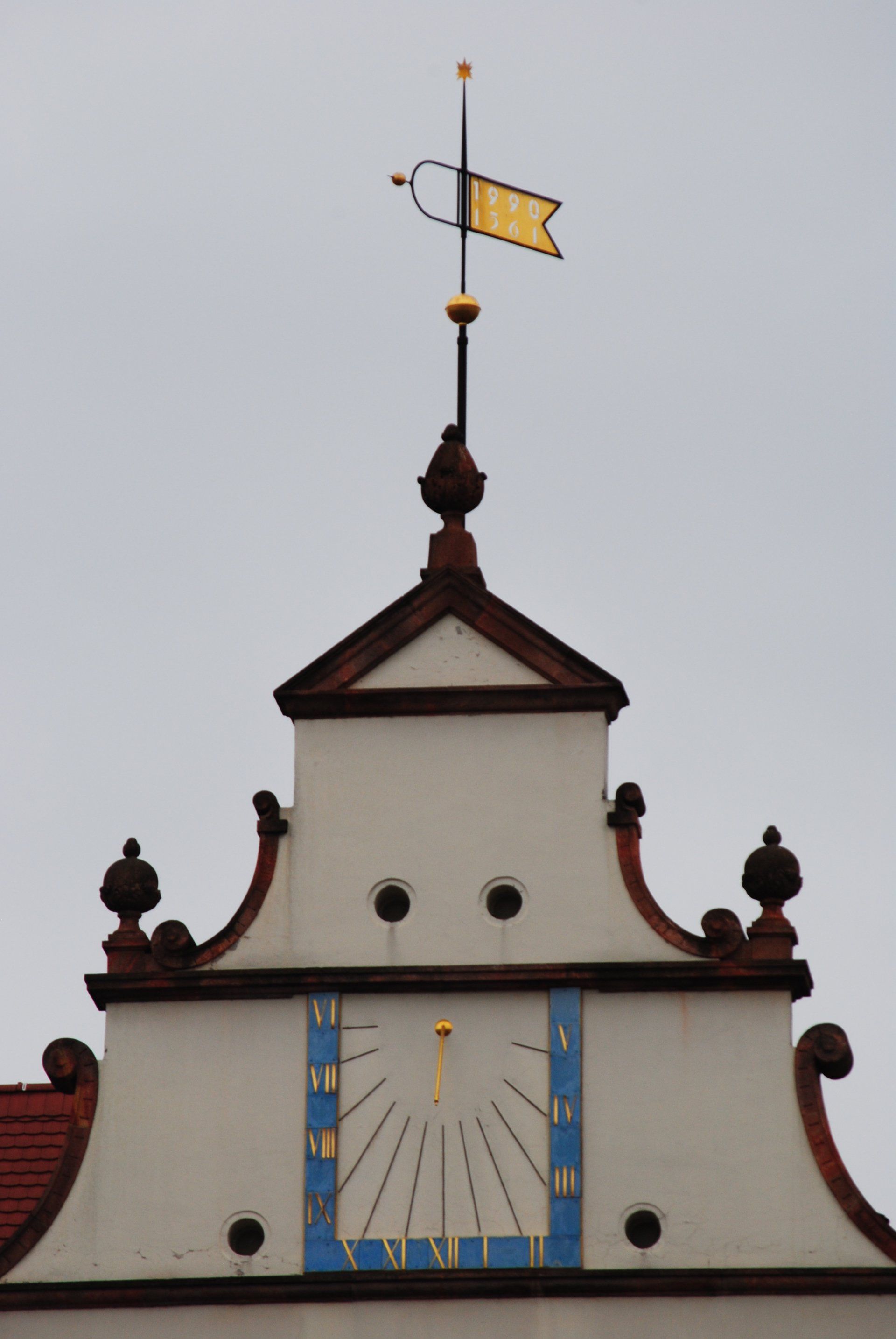 A weather vane on top of a building with a clock on it