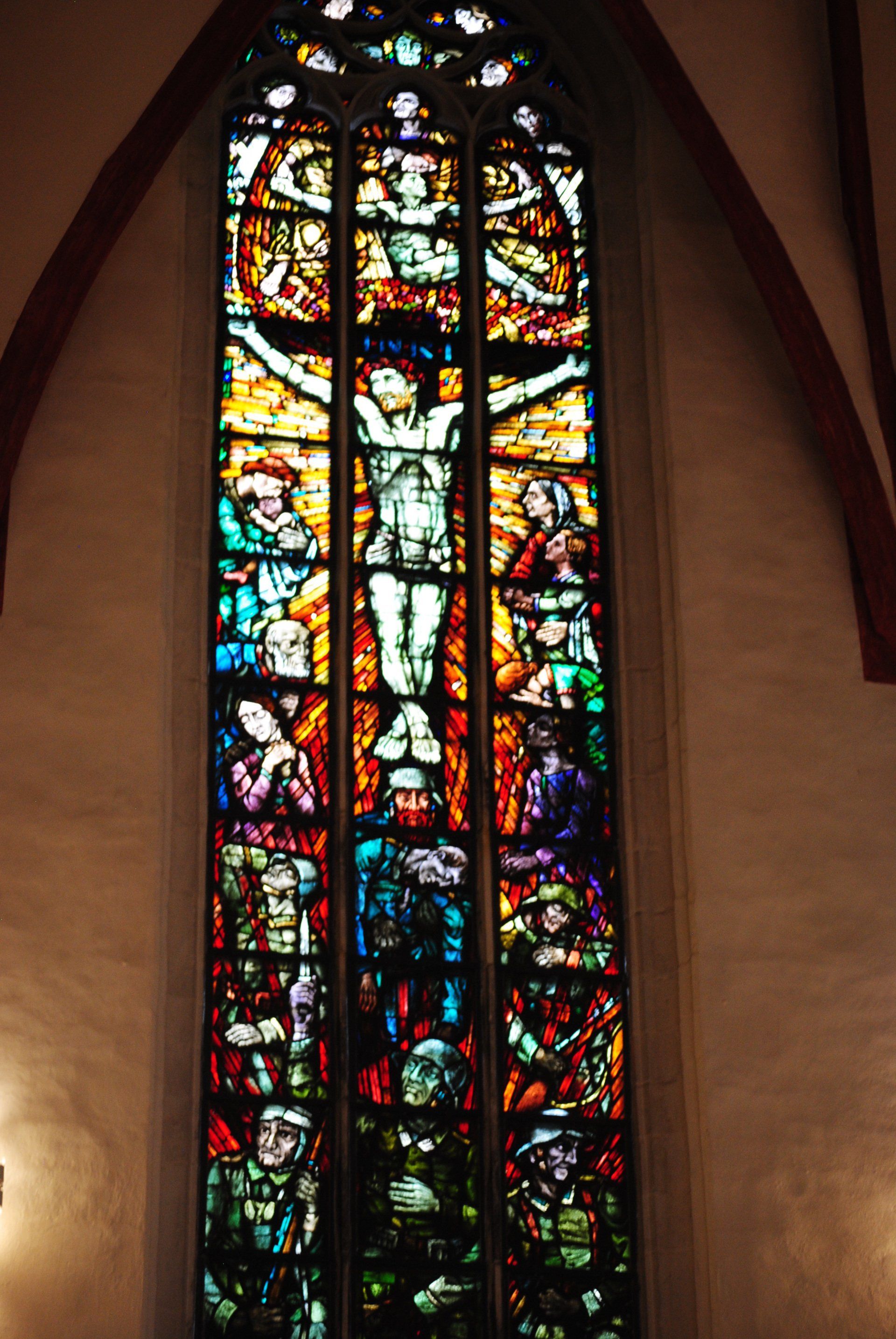 A stained glass window in a church shows jesus on the cross