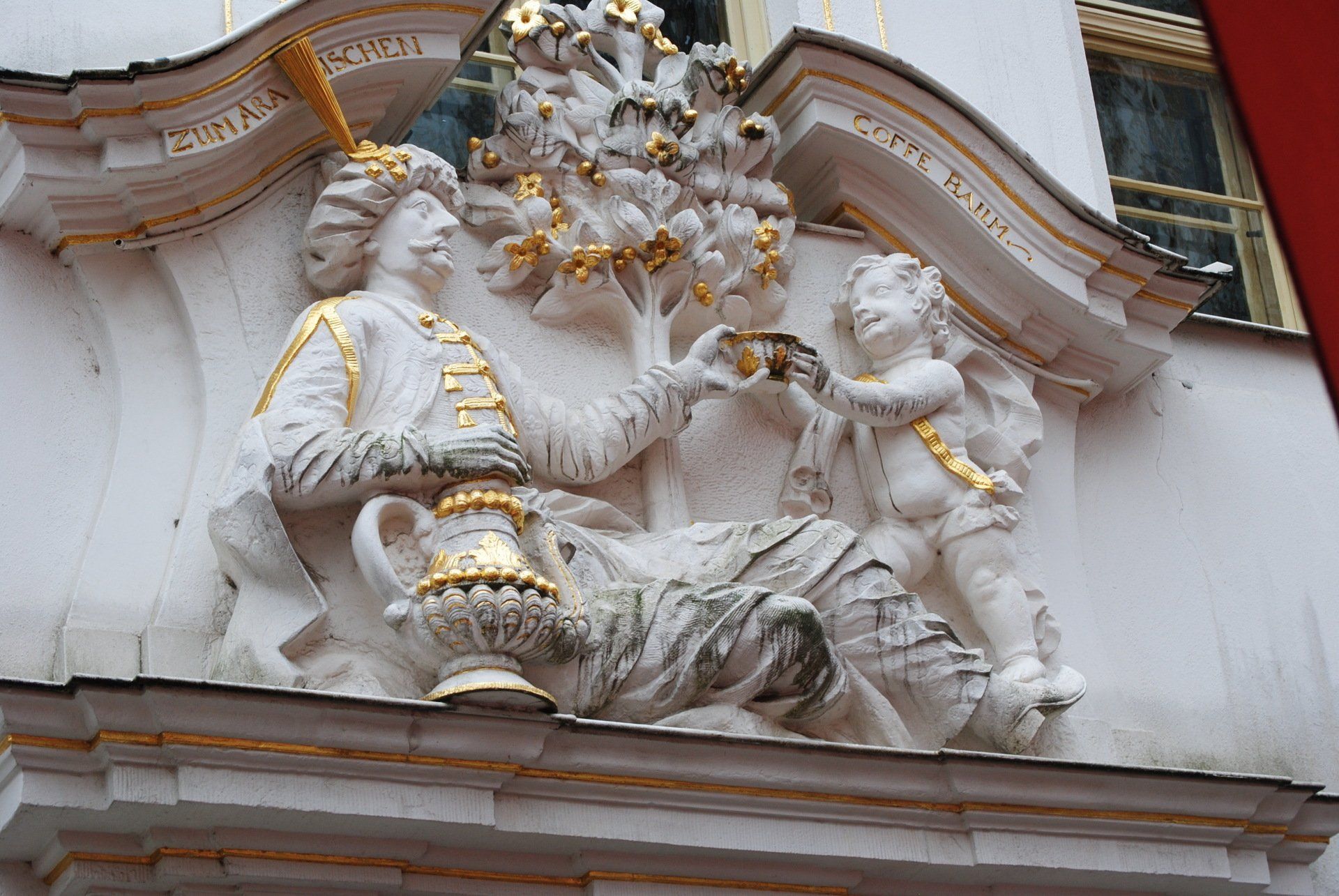 A statue on the side of a building shows a man and a woman