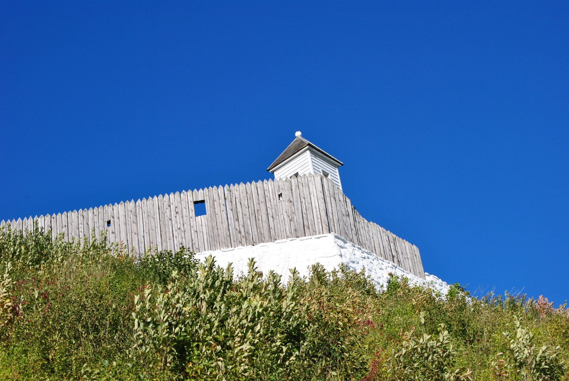 A small building on top of a hill with a blue sky in the background