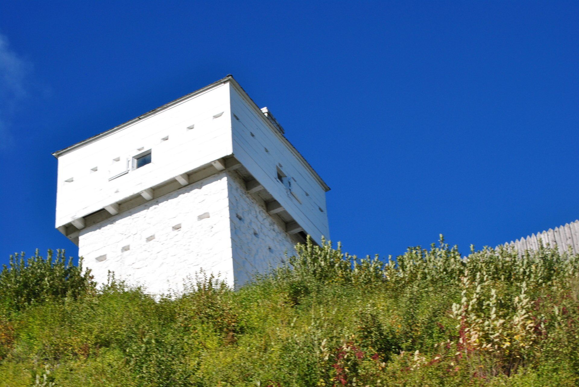 A white building is sitting on top of a grassy hill.