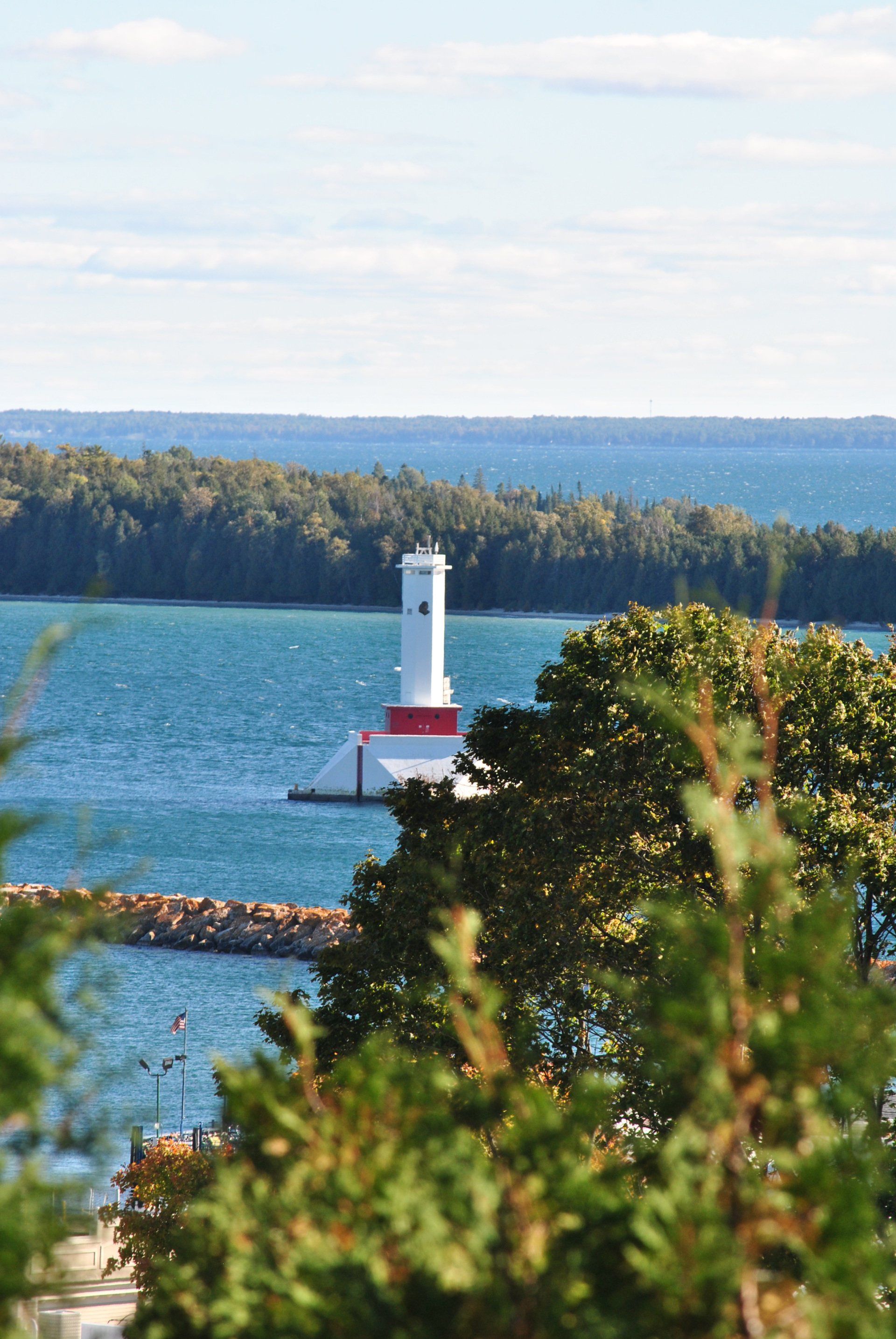 A lighthouse in the middle of a body of water surrounded by trees.