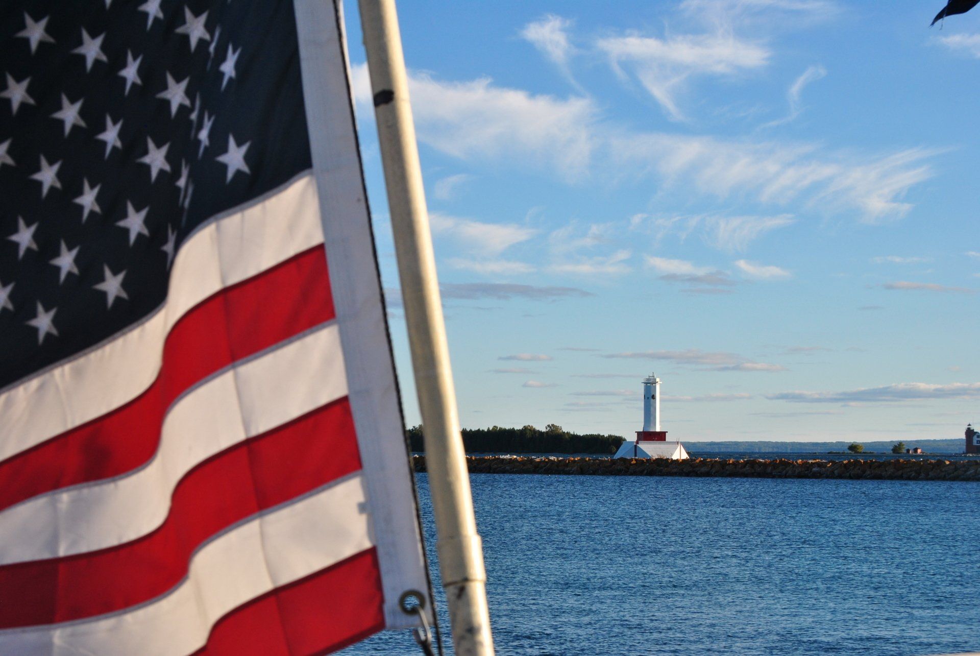 An american flag is flying in front of a body of water