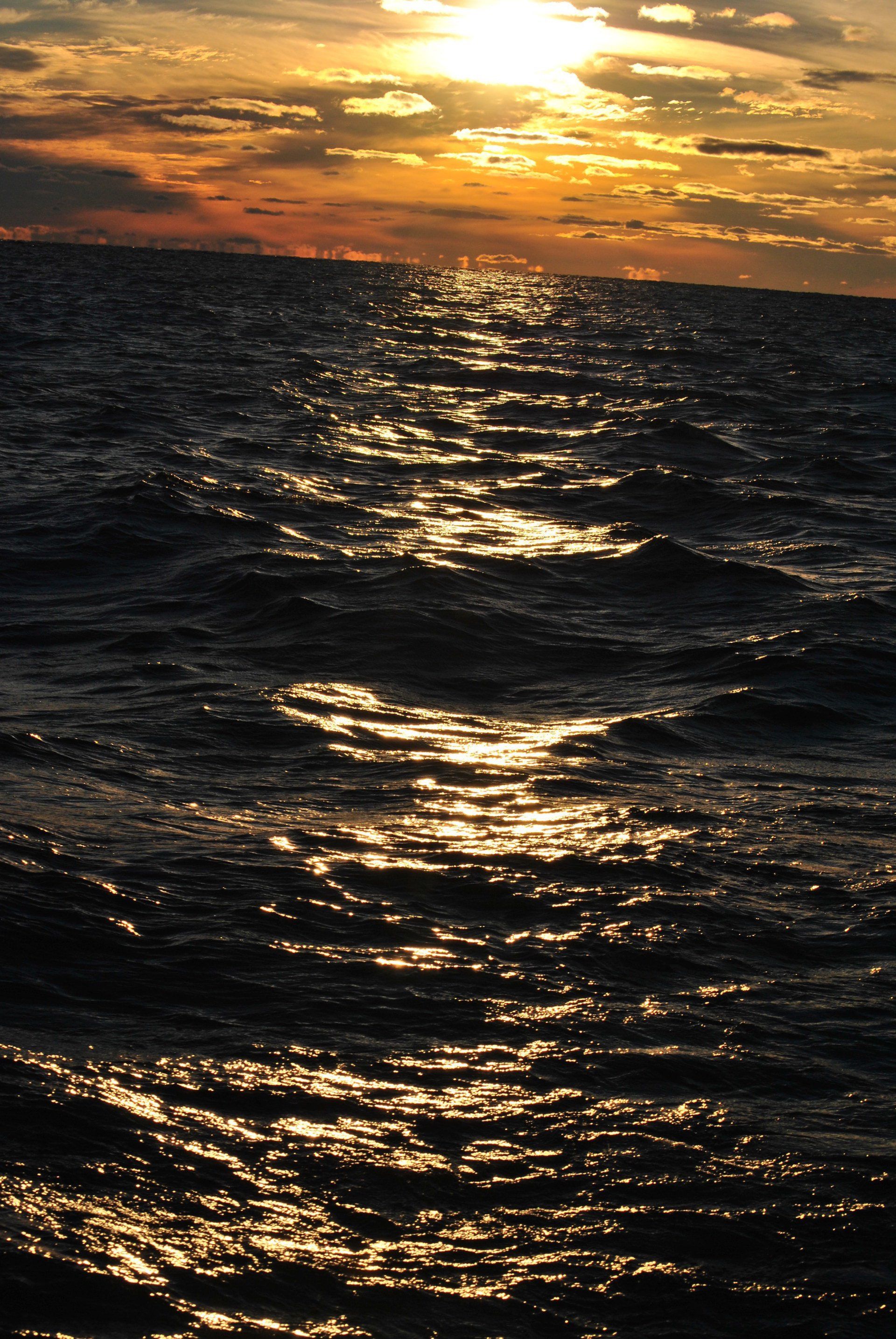 A sunset over the ocean with the sun reflected in the water