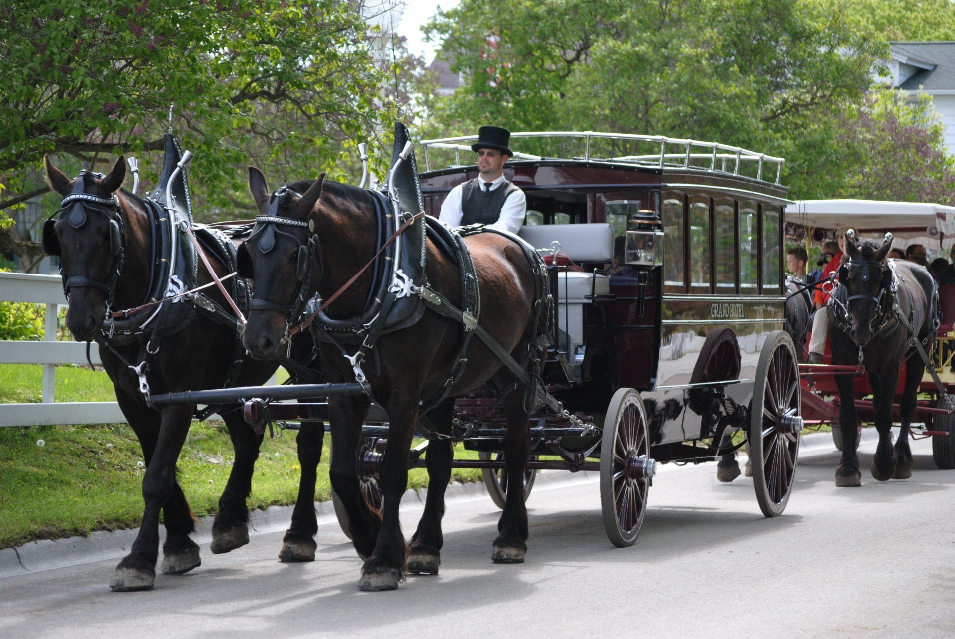 A man in a top hat is driving a horse drawn carriage