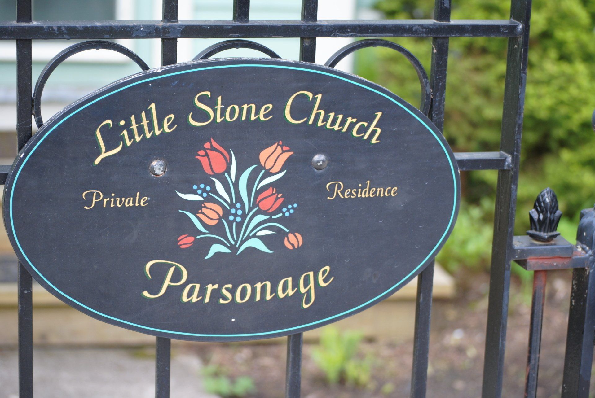 A sign on a gate that says little stone church parsonage