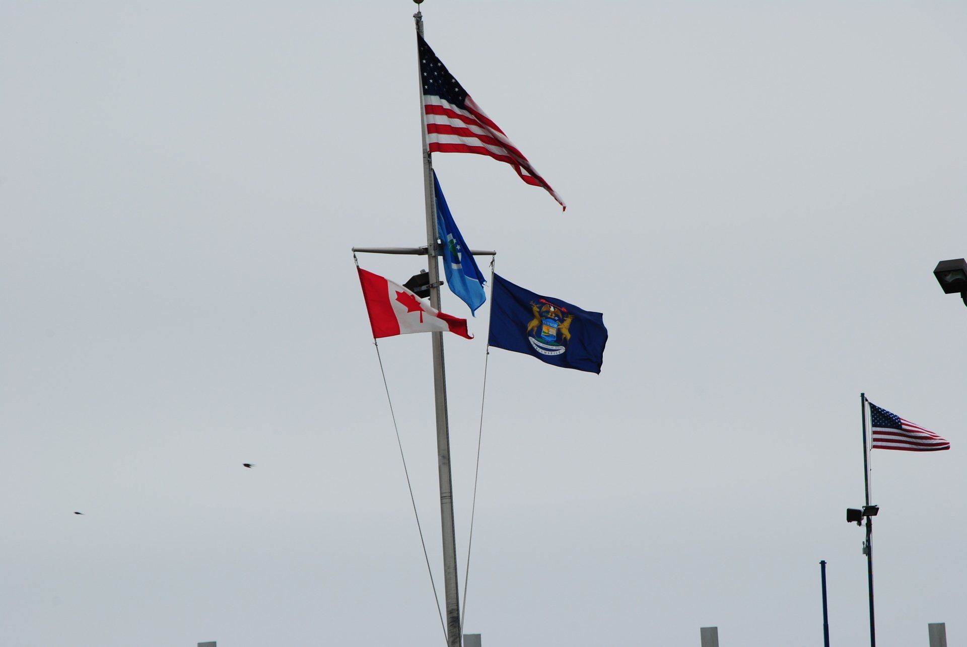 Three flags are flying in the wind on a pole