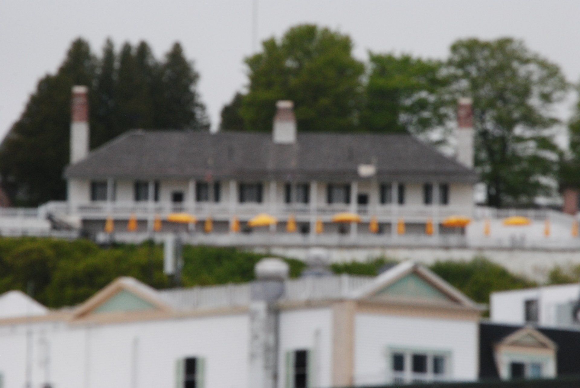 A large white house with a gray roof is surrounded by trees