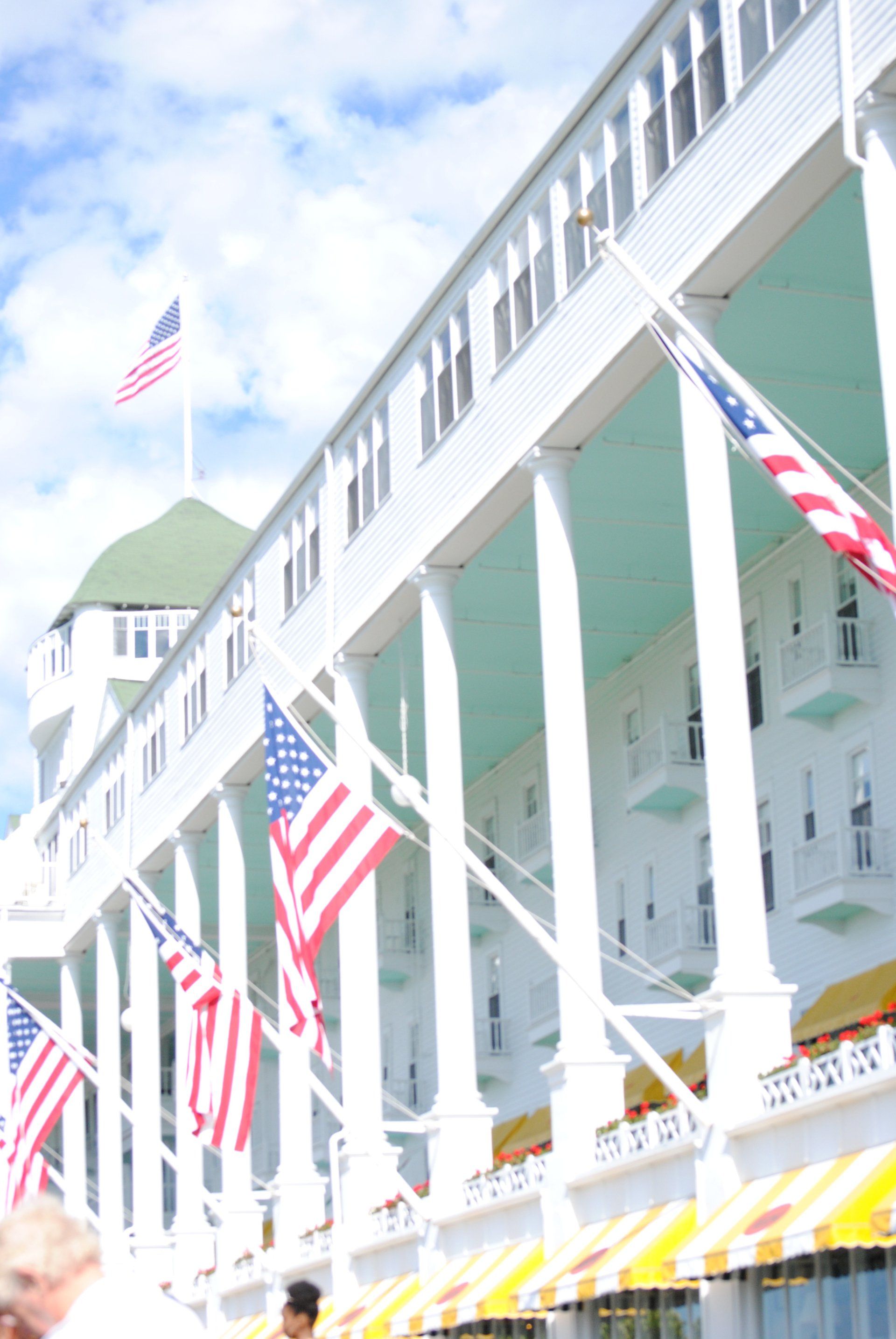A row of american flags are hanging from the side of a building