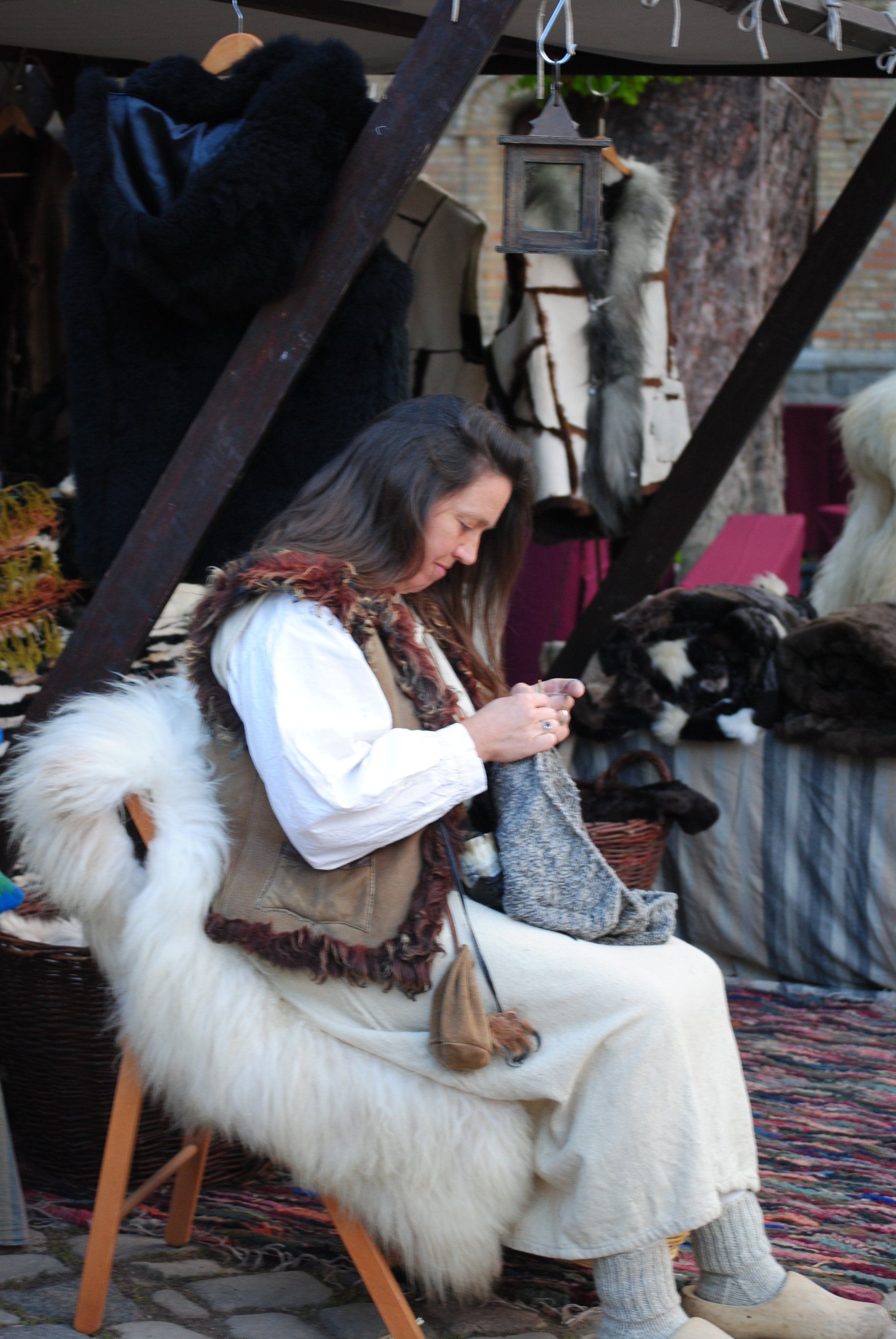 A woman is sitting in a chair knitting a scarf.