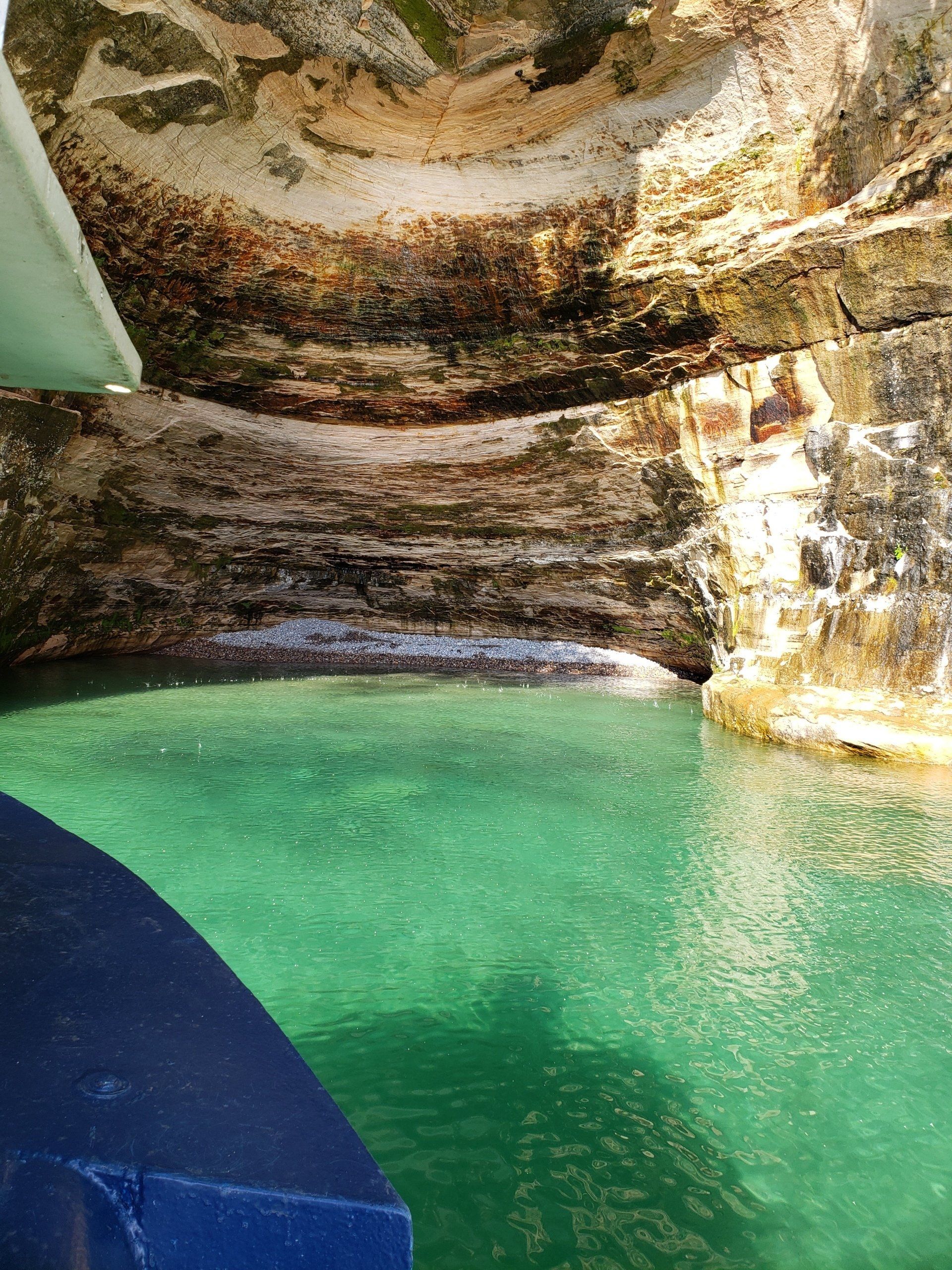 A boat is floating on top of a body of water surrounded by rocks.