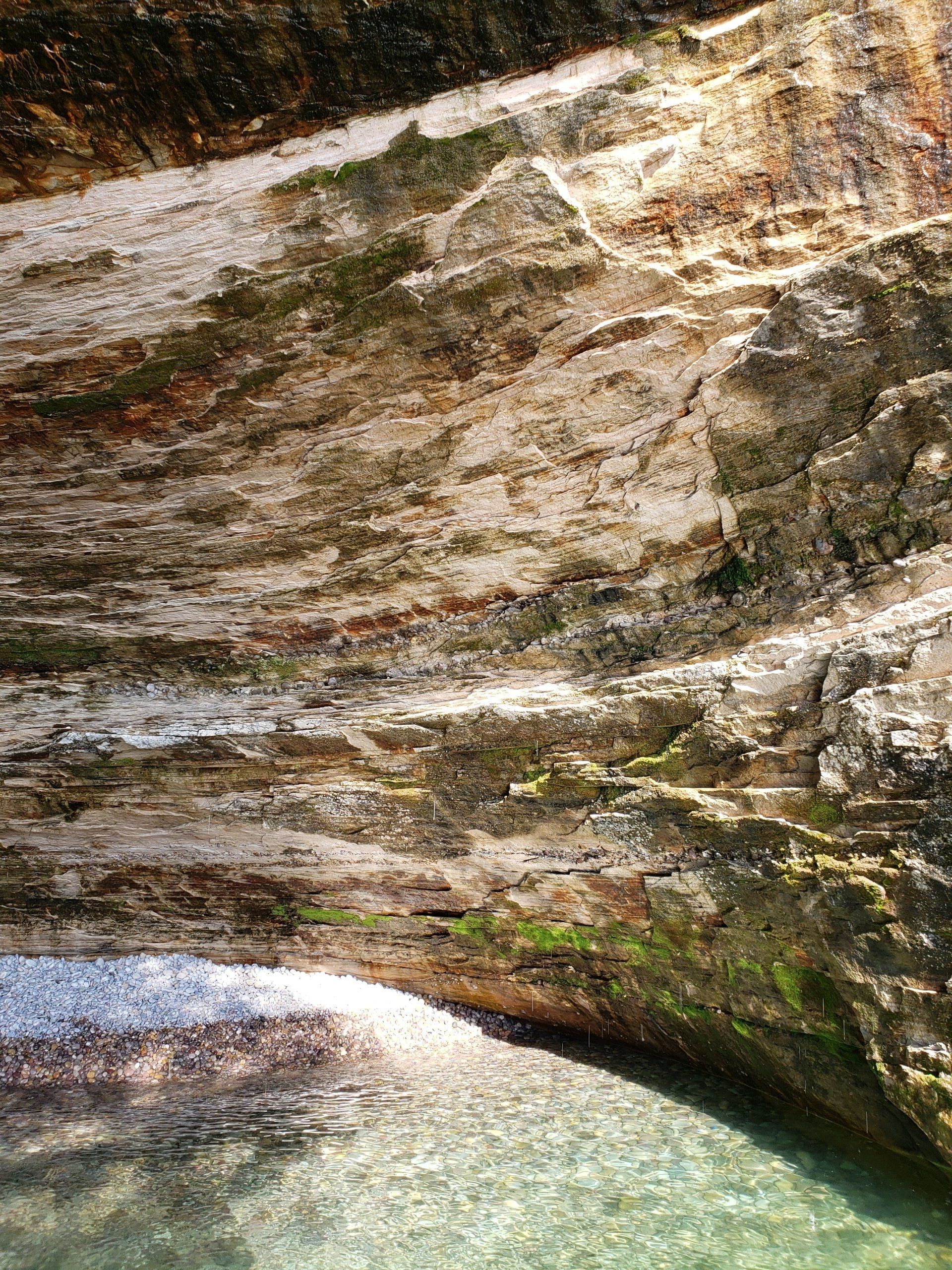 A close up of a rocky cliff next to a body of water.