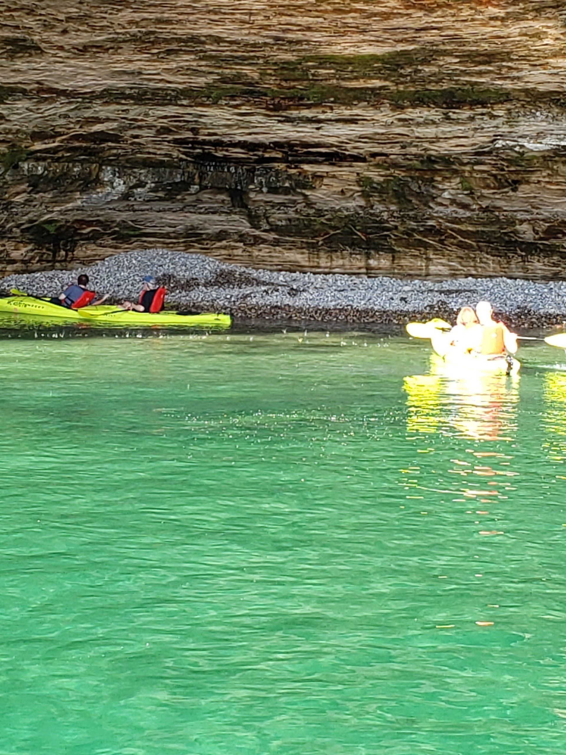 A couple of people are kayaking on a lake.