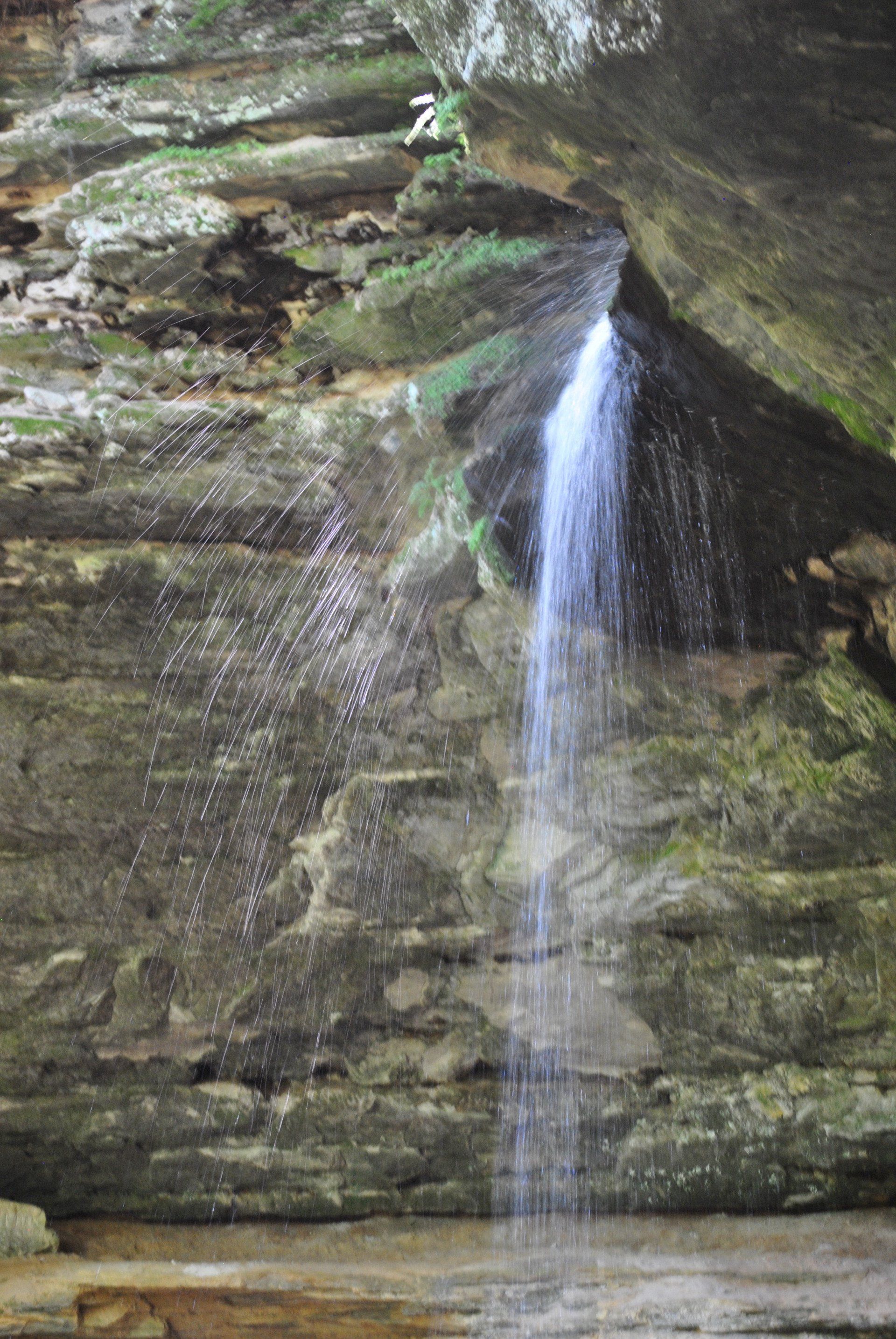A waterfall is coming down a rocky cliff in the woods.