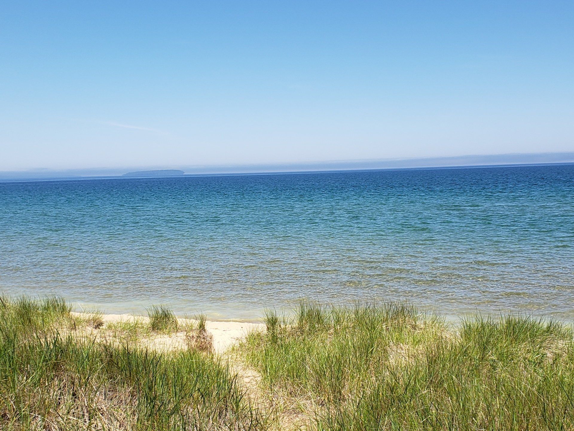 A path leading to a beach with a large body of water in the background.