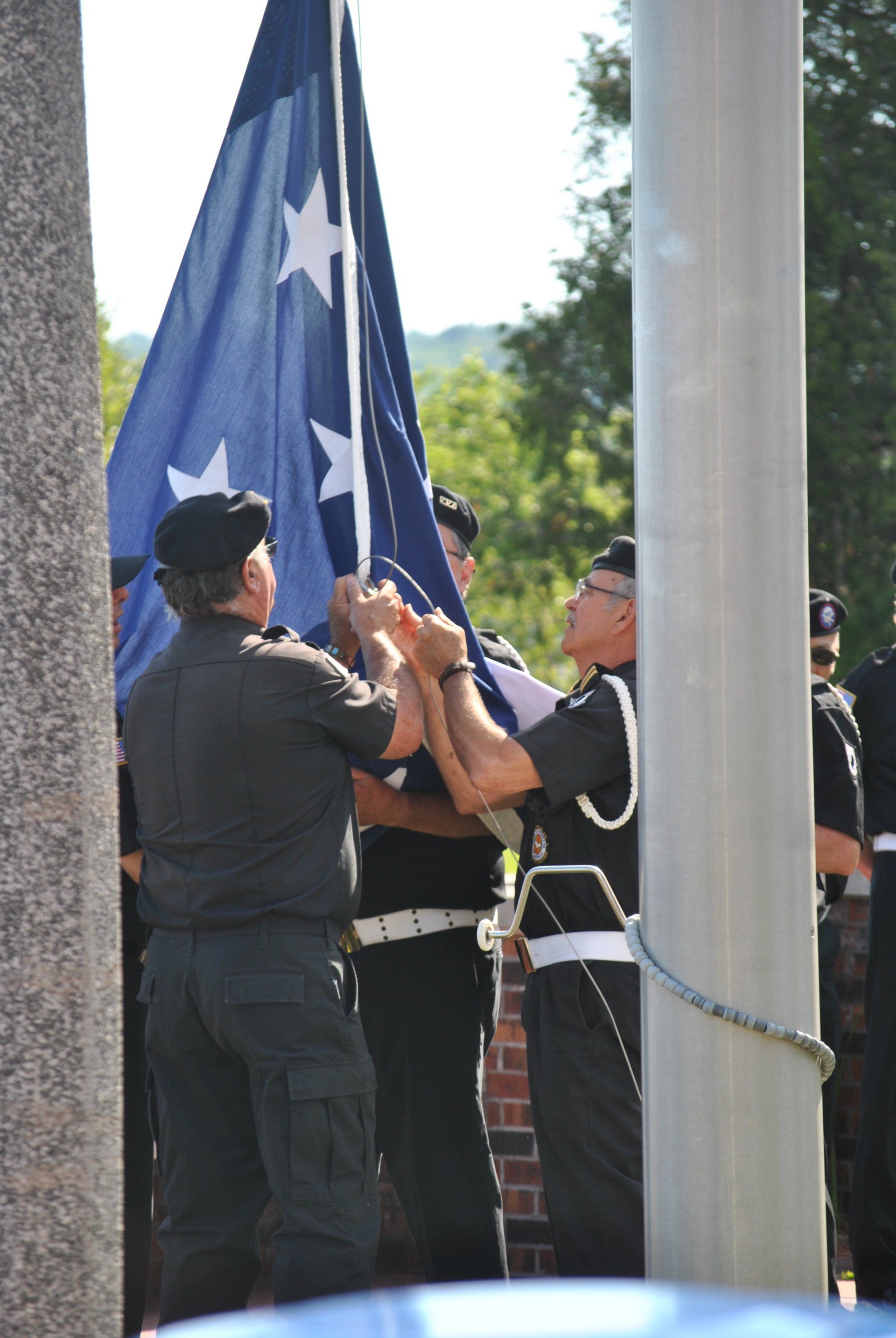 A group of men are raising an american flag