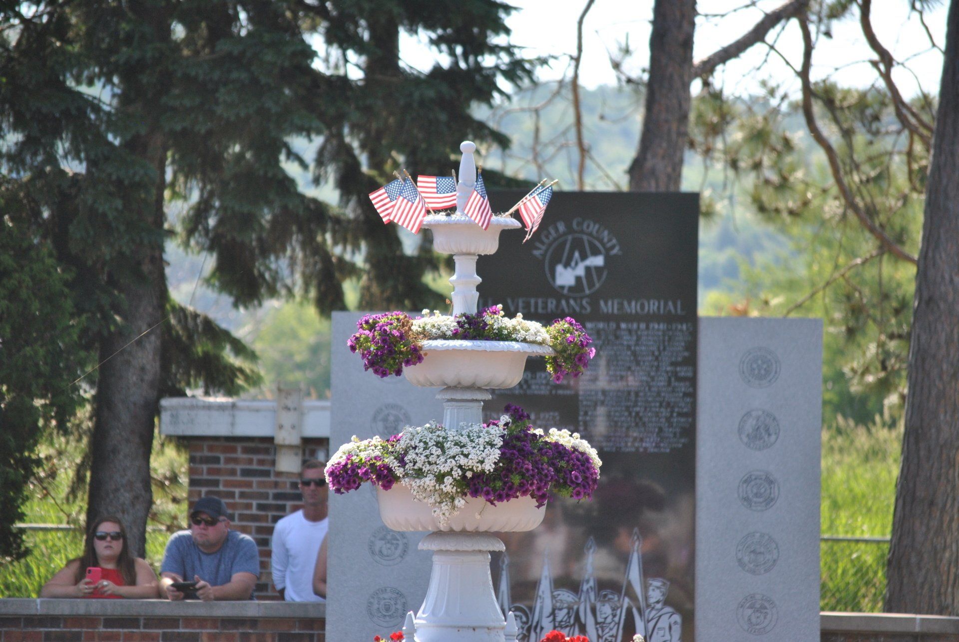 A fountain with flowers and american flags on top of it